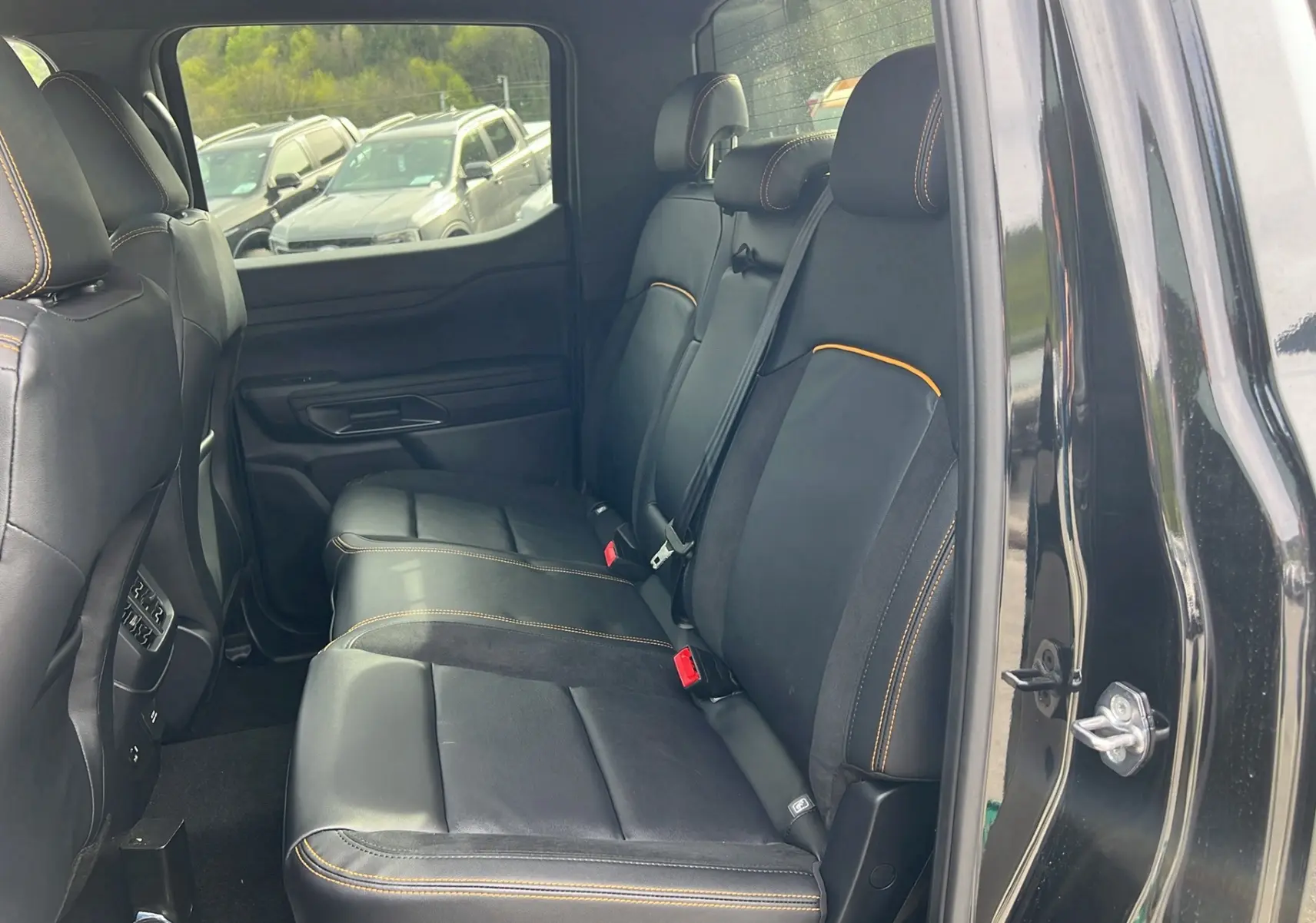 Vue intérieure côté droit montrant la banquette arrière en cuir noir avec surpiqûres orange du Ford Ranger Wildtrak 2026.