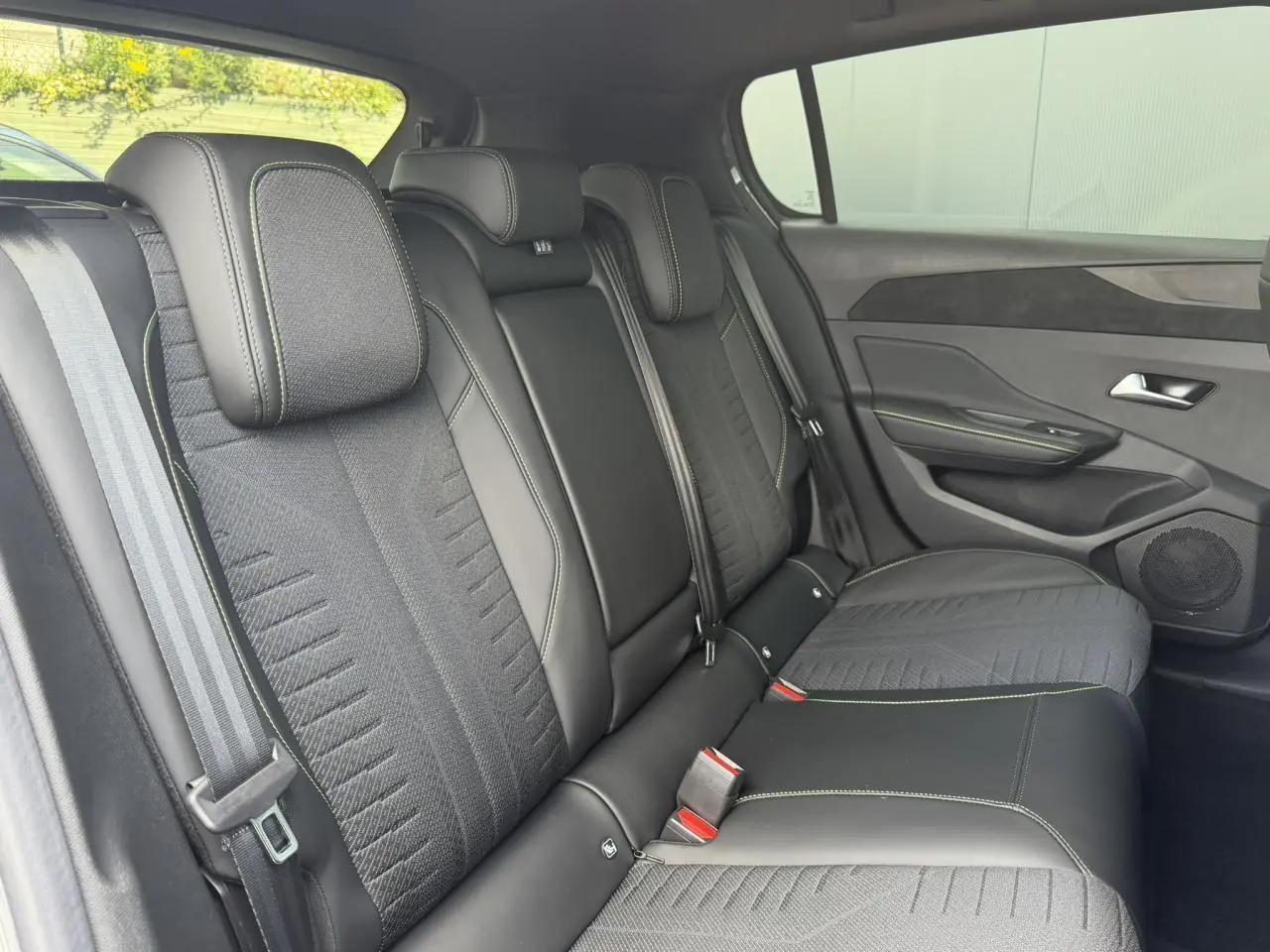 Vue latérale droite de la banquette arrière noire avec surpiqûres vert Adamite dans une Peugeot 308 gris Selenium.
