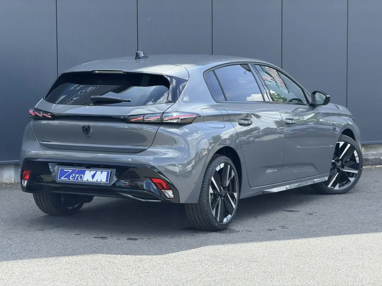 Peugeot 308 NV Hybrid gris Selenium vue 3/4 arrière droit, jantes bi-tons et feux arrière LED 3 griffes.