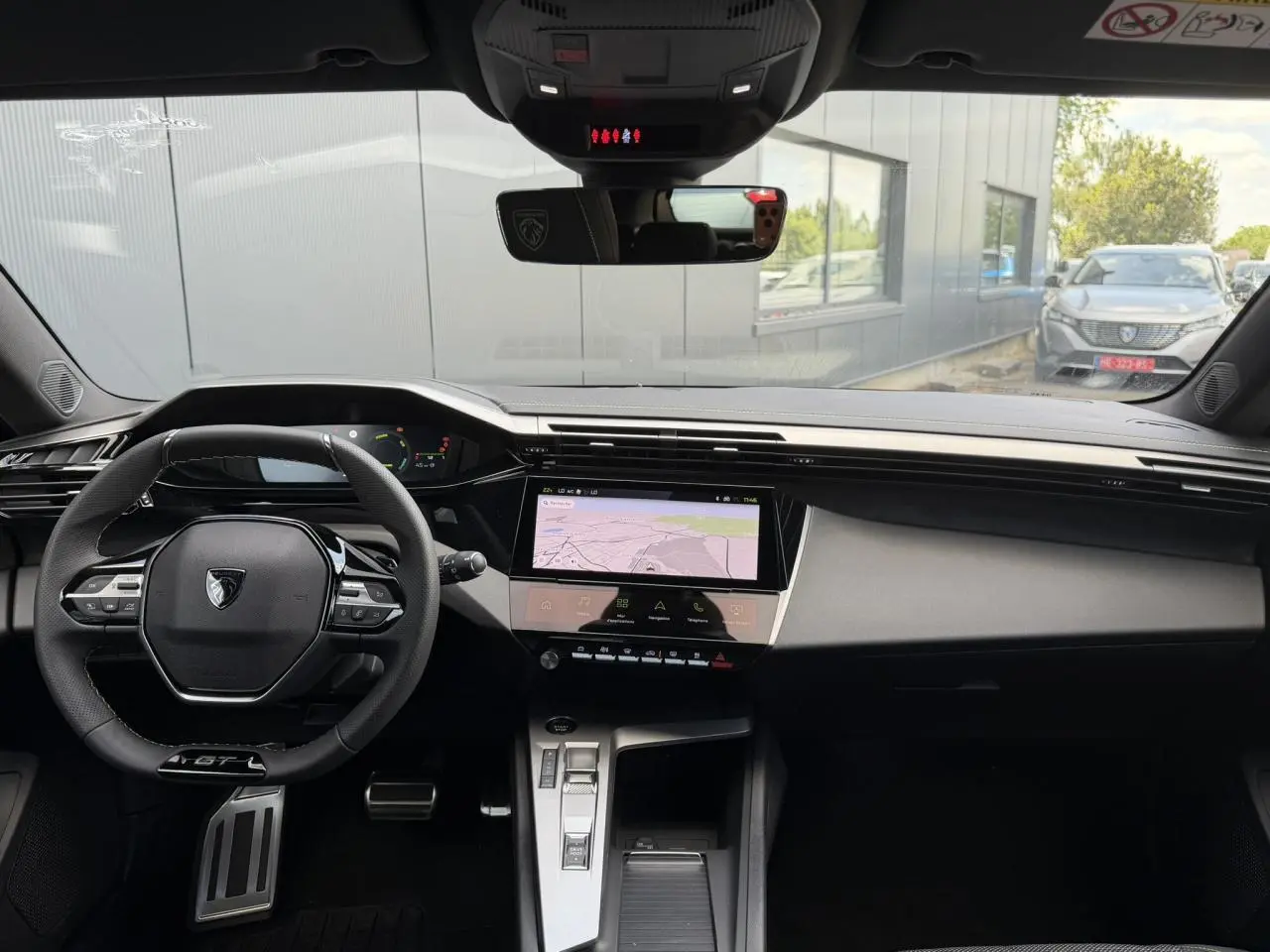 Vue intérieure avant de la Peugeot 308 GT Hybrid 2026 gris Selenium, volant compact GT et écran tactile central.