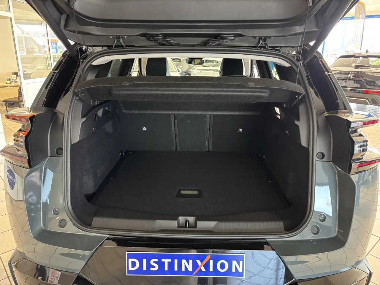 Coffre ouvert vu de l'arrière d'un Citroën C5 Aircross vert métallisé avec feux arrière LED et hayon levé.