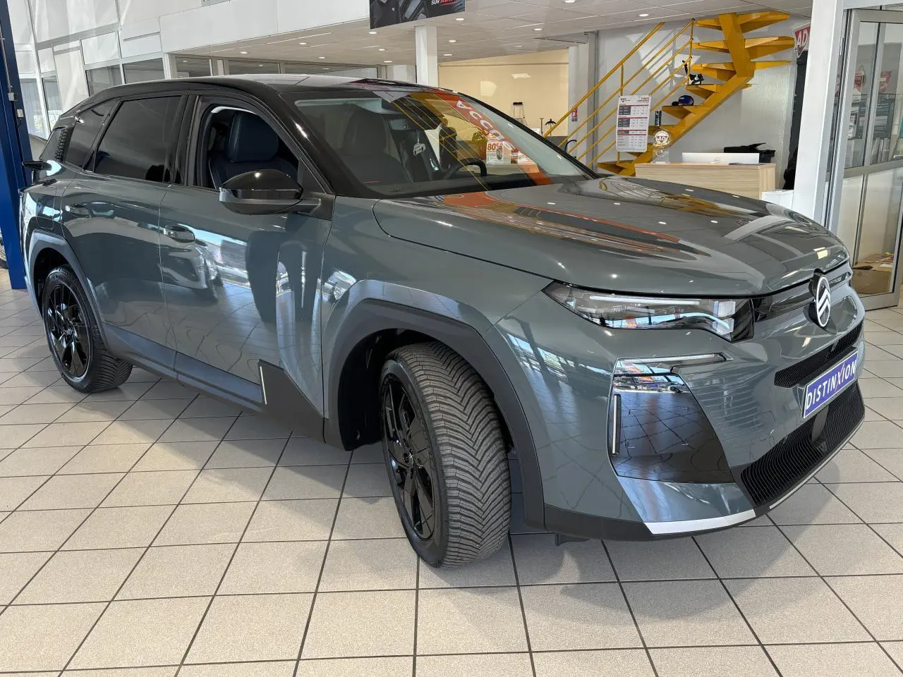 Vue 3/4 avant gauche du Citroën C5 Aircross vert avec jantes alliage noires et calandre noir brillant en showroom.