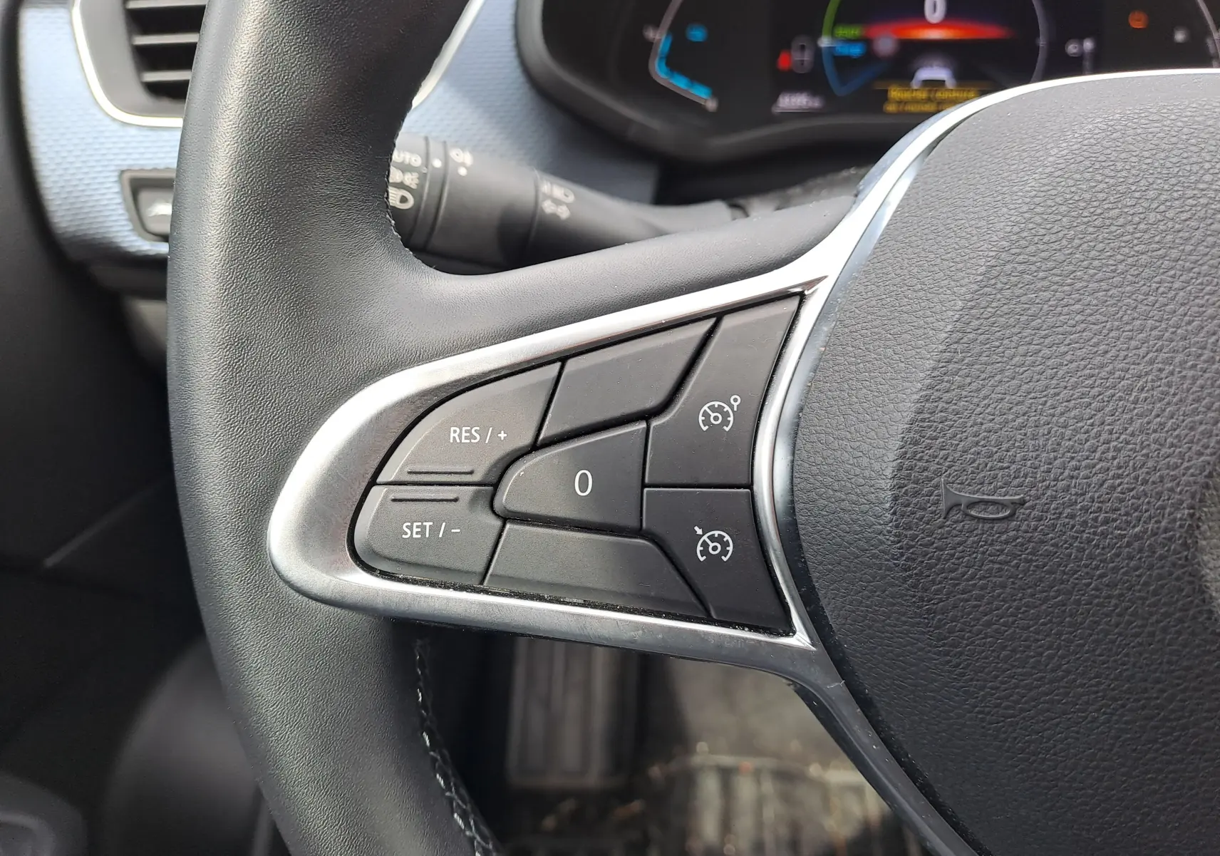 Gros plan sur les commandes de régulateur de vitesse au volant noir du Renault Arkana 2023 hybride.