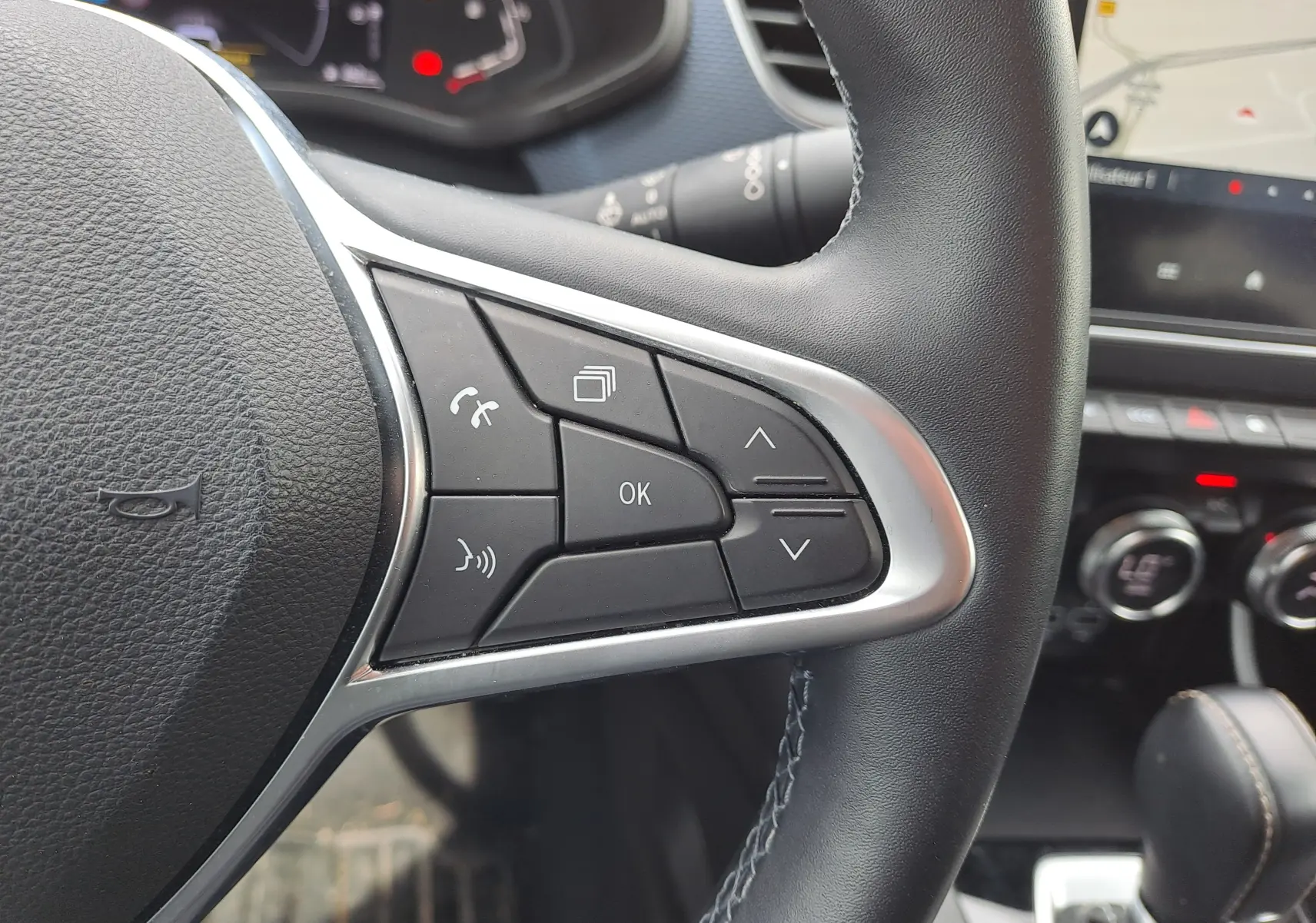 Gros plan sur les commandes à gauche du volant du Renault Arkana 2023, intérieur noir avec écran tactile et levier de vitesse visible.