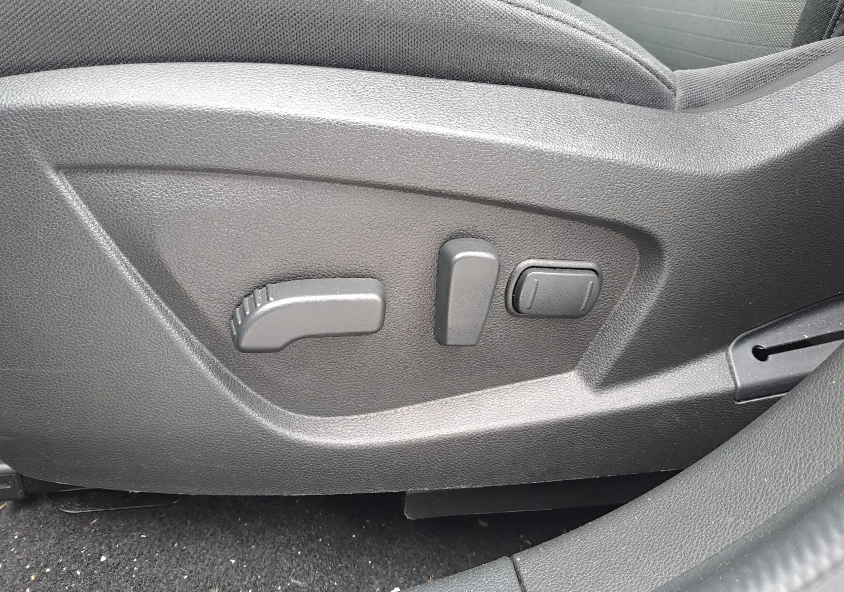 Commandes électriques de réglage du siège conducteur sur Renault Arkana bleu Zanzibar 2023, intérieur tissu noir.