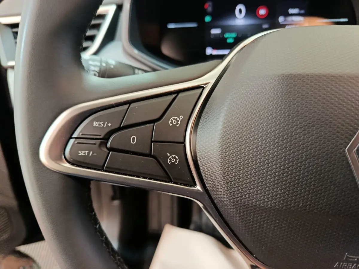 Gros plan sur le volant cuir synthétique de la Renault Clio 2025 avec commandes de régulateur de vitesse côté gauche.