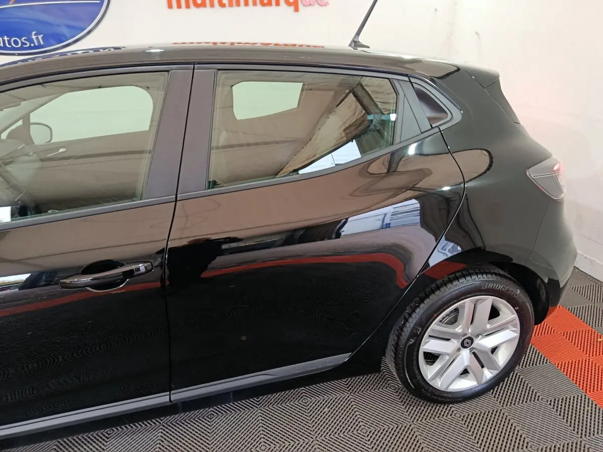 Vue latérale droite d'une Renault Clio noire brillante, mettant en valeur la porte arrière et la roue arrière en alliage.