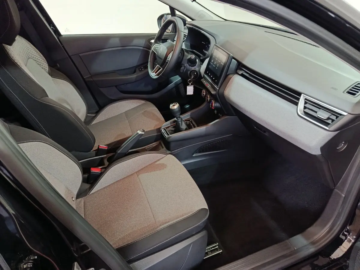 Intérieur avant droit de la Renault Clio Evolution Blue dCi 100 2025, sièges gris et tableau de bord moderne avec écran tactile.