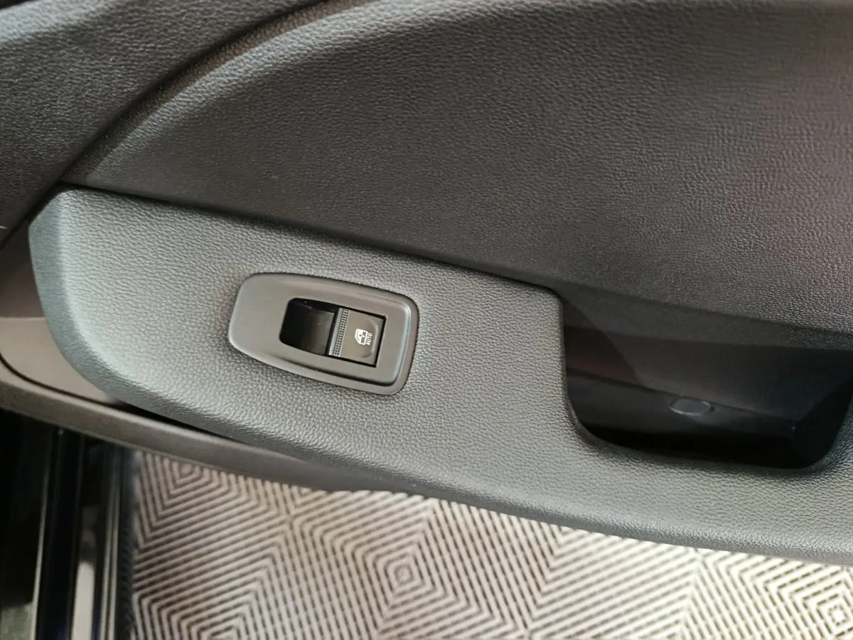 Détail de la commande de lève-vitre électrique sur la porte intérieure noire d'une Renault Clio Evolution Blue dCi 100 2025.