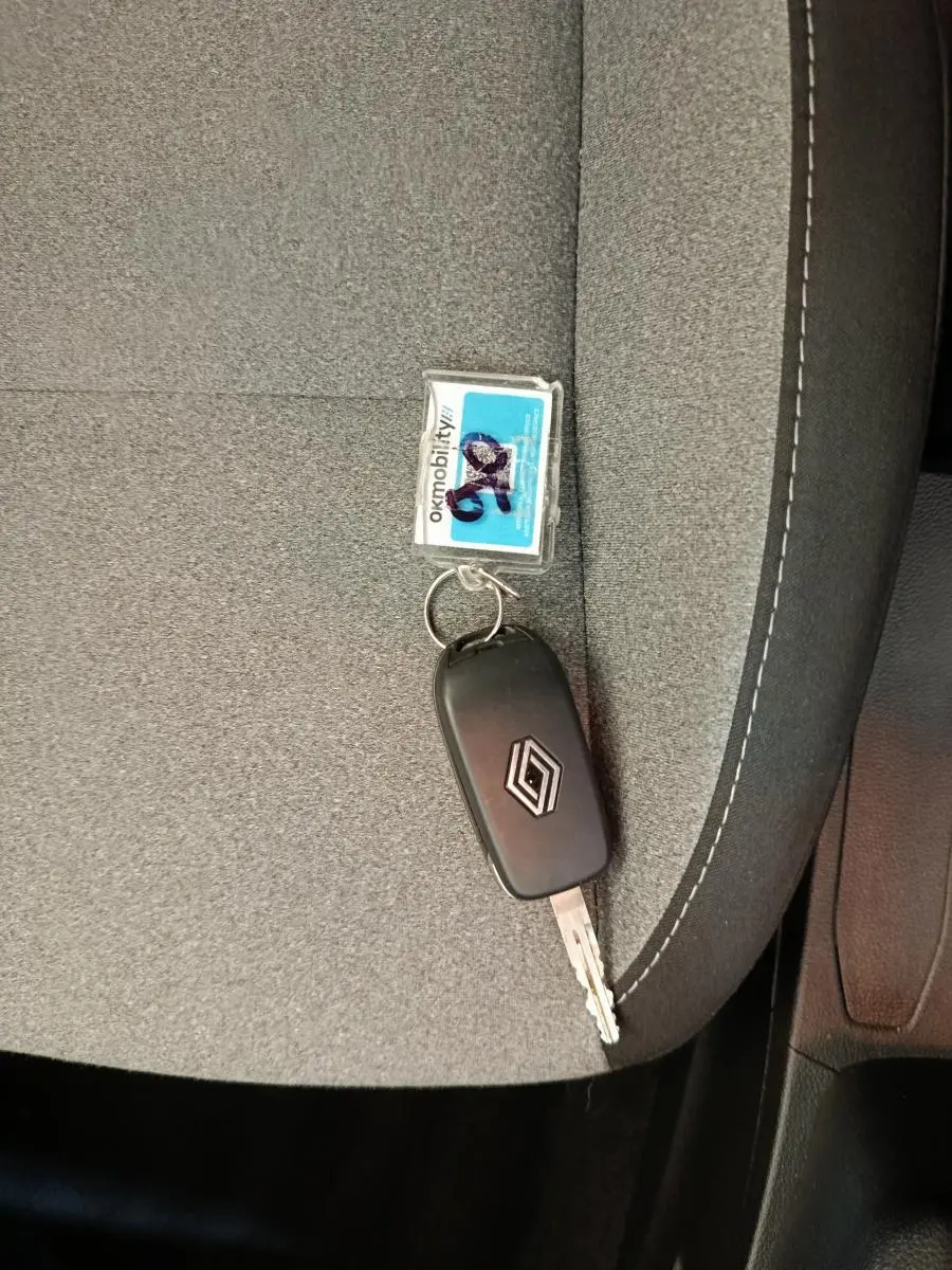 Clé Renault posée sur un siège tissu gris avec surpiqûres blanches, intérieur sobre et fonctionnel.