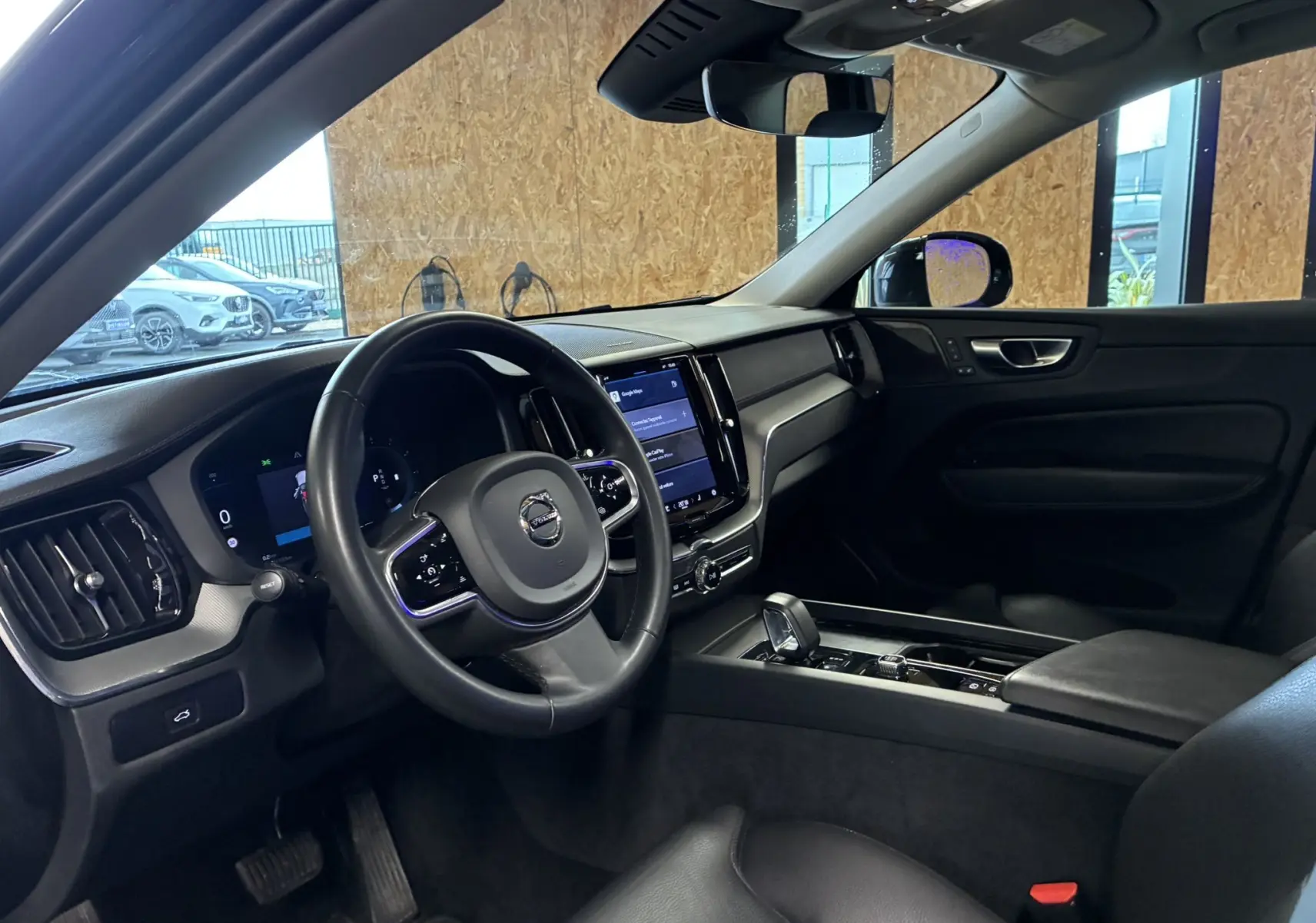 Intérieur noir du Volvo XC60 2023 vu côté conducteur, avec tableau de bord digital et console centrale moderne.