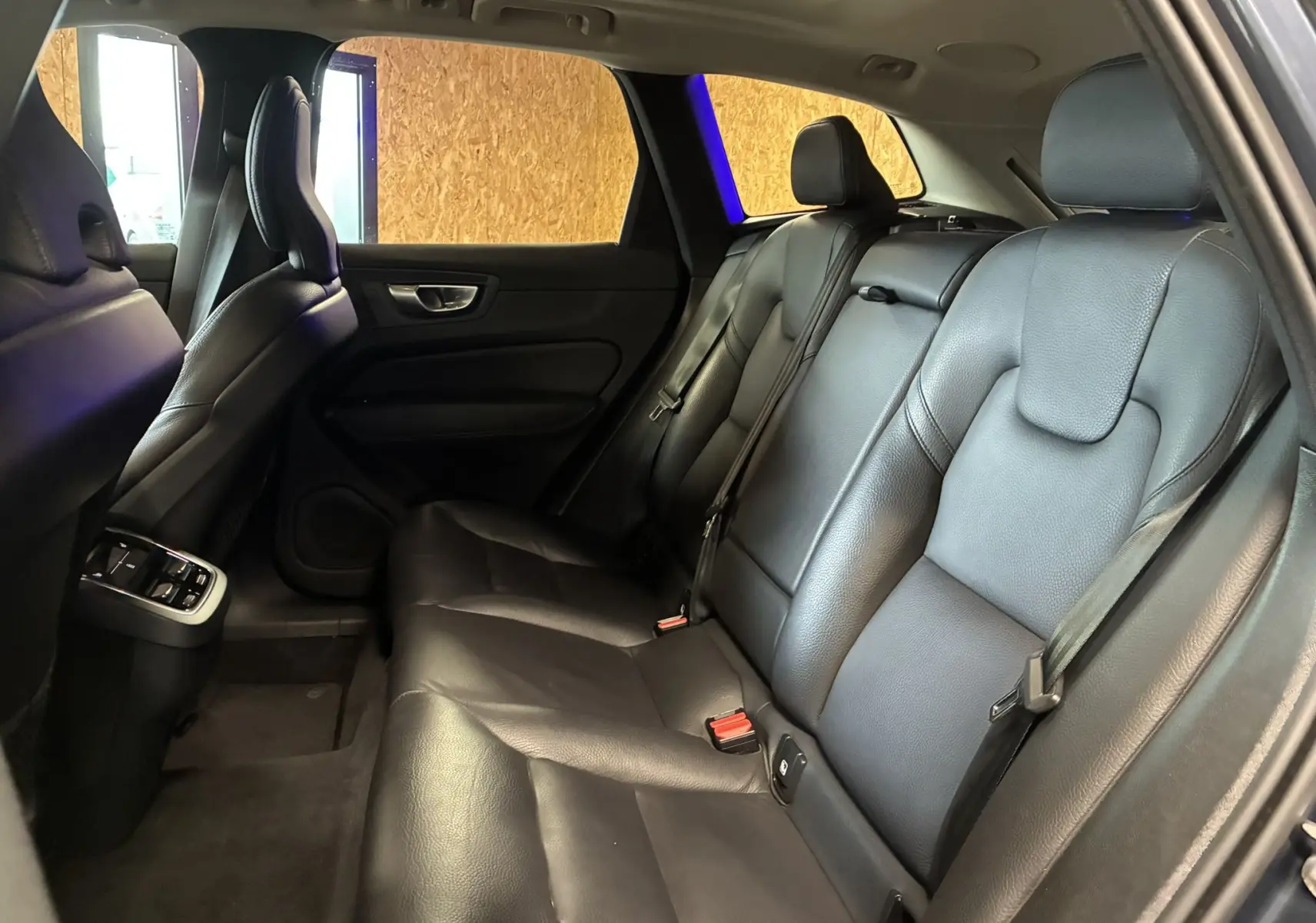 Vue intérieure côté droit des sièges arrière en cuir noir du Volvo XC60 2023, avec ceintures de sécurité visibles.