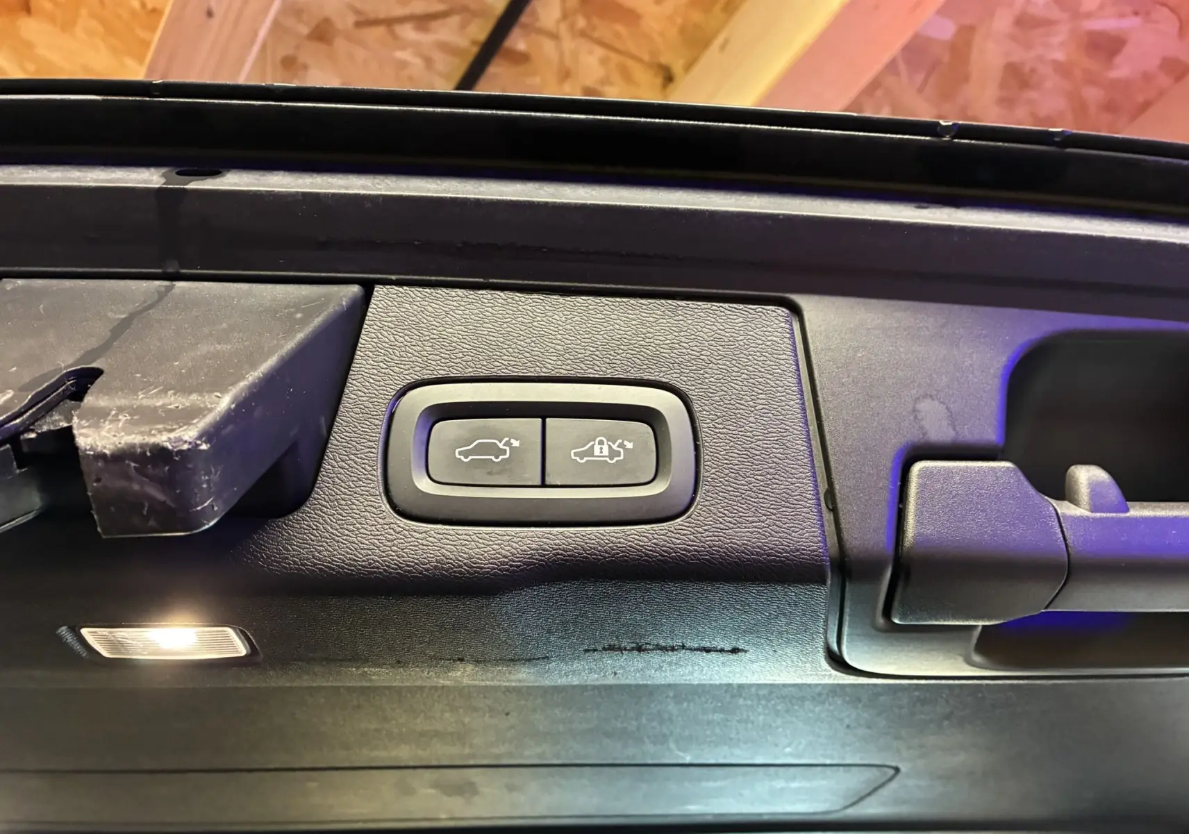 Gros plan sur les boutons d'ouverture et de verrouillage électrique du hayon du Volvo XC60 bleu, vue intérieure du coffre.