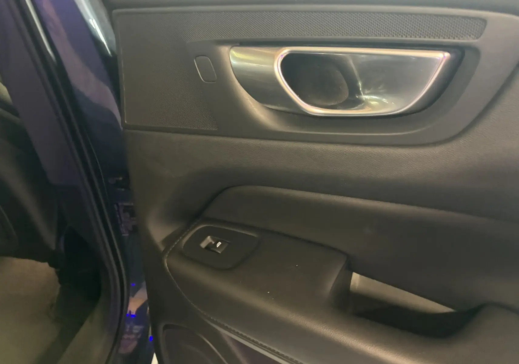Gros plan sur la poignée intérieure et le panneau de porte côté conducteur du Volvo XC60 bleu 2023.