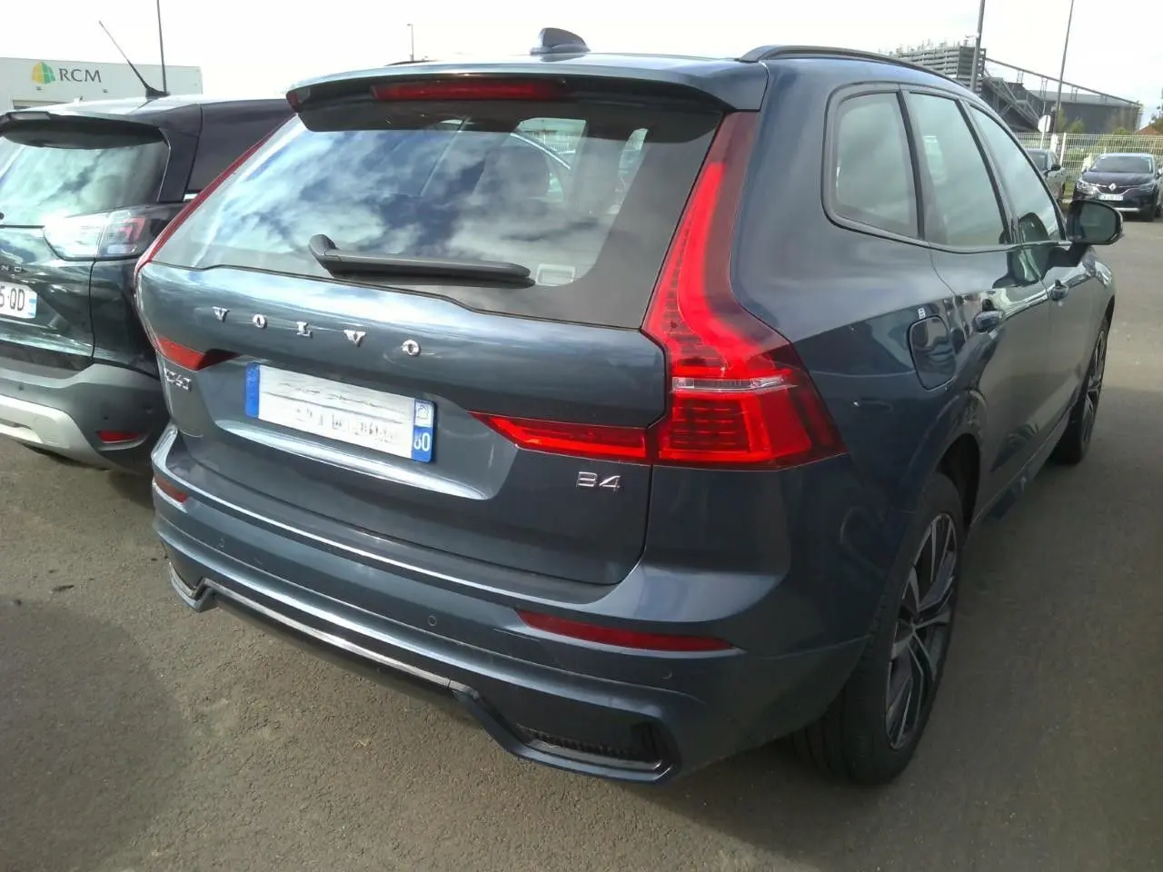 Volvo XC60 bleu vue 3/4 avant droit, calandre noire laquée et jantes alliage 20 pouces en Y noir/diamant.