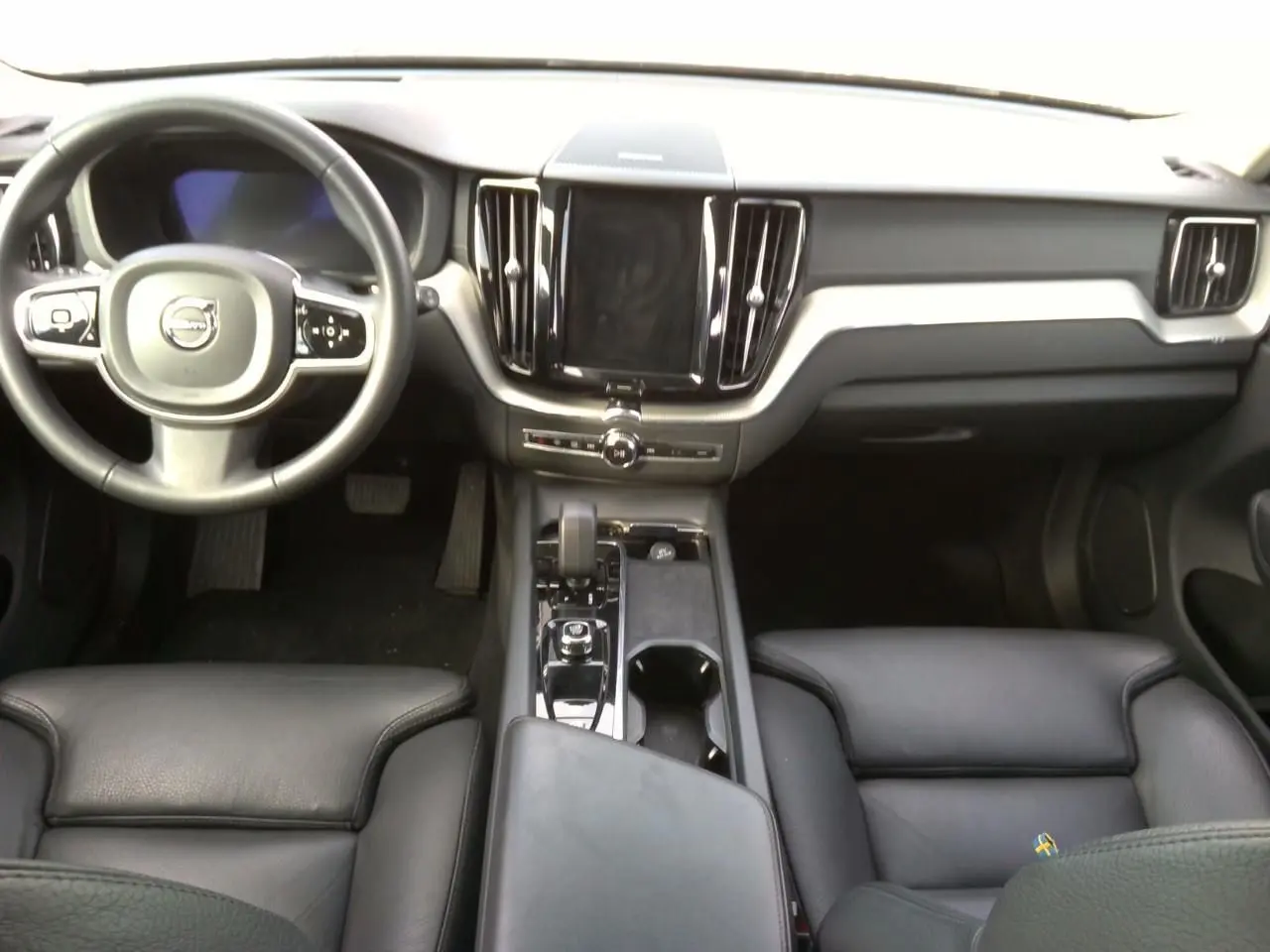 Vue latérale droite d'un Volvo XC60 bleu 2023 avec jantes alliage 20'' bicolores et rétroviseurs noirs laqués.