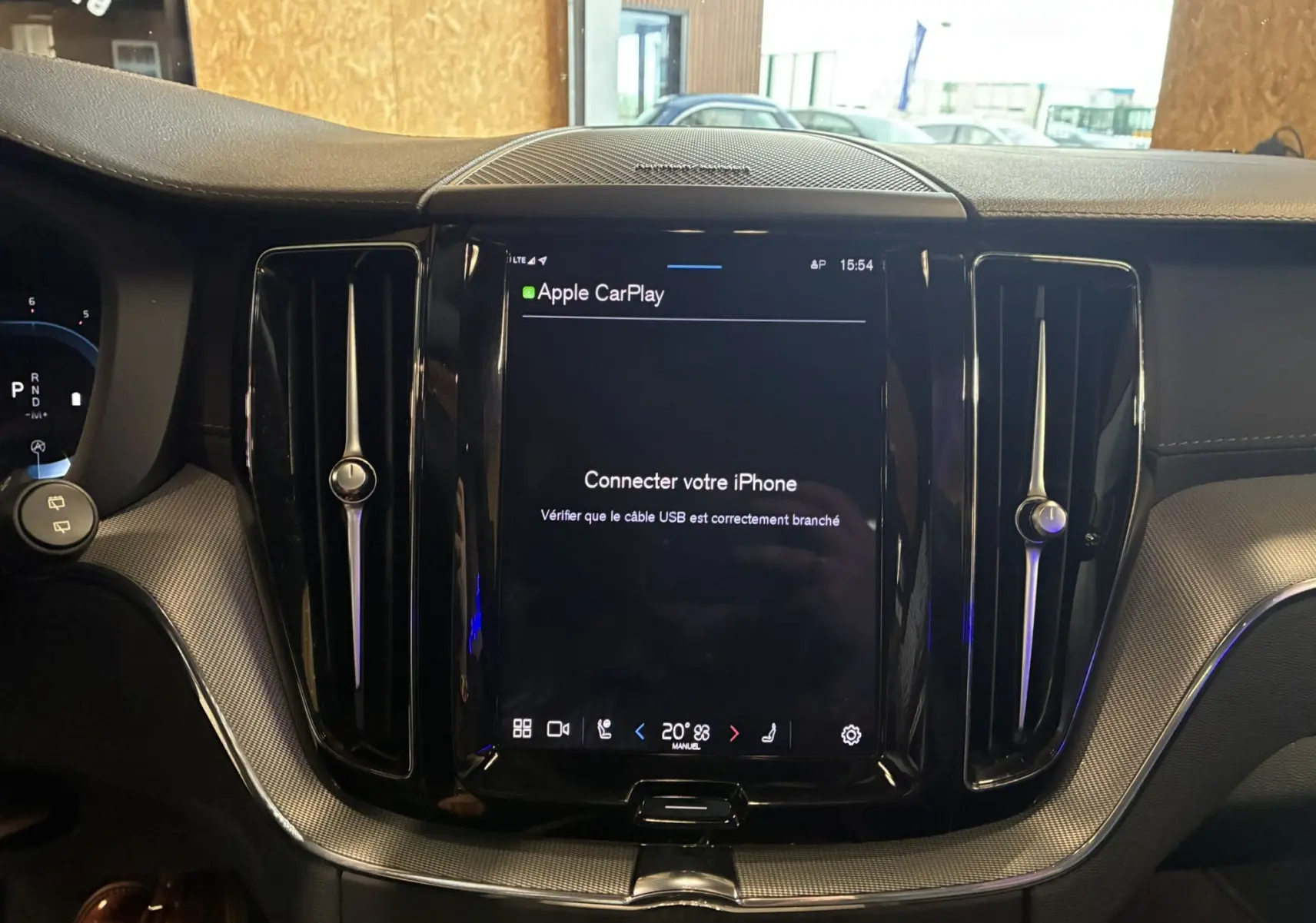 Vue rapprochée de la console centrale noire brillante du Volvo XC60 avec écran tactile Apple CarPlay allumé.