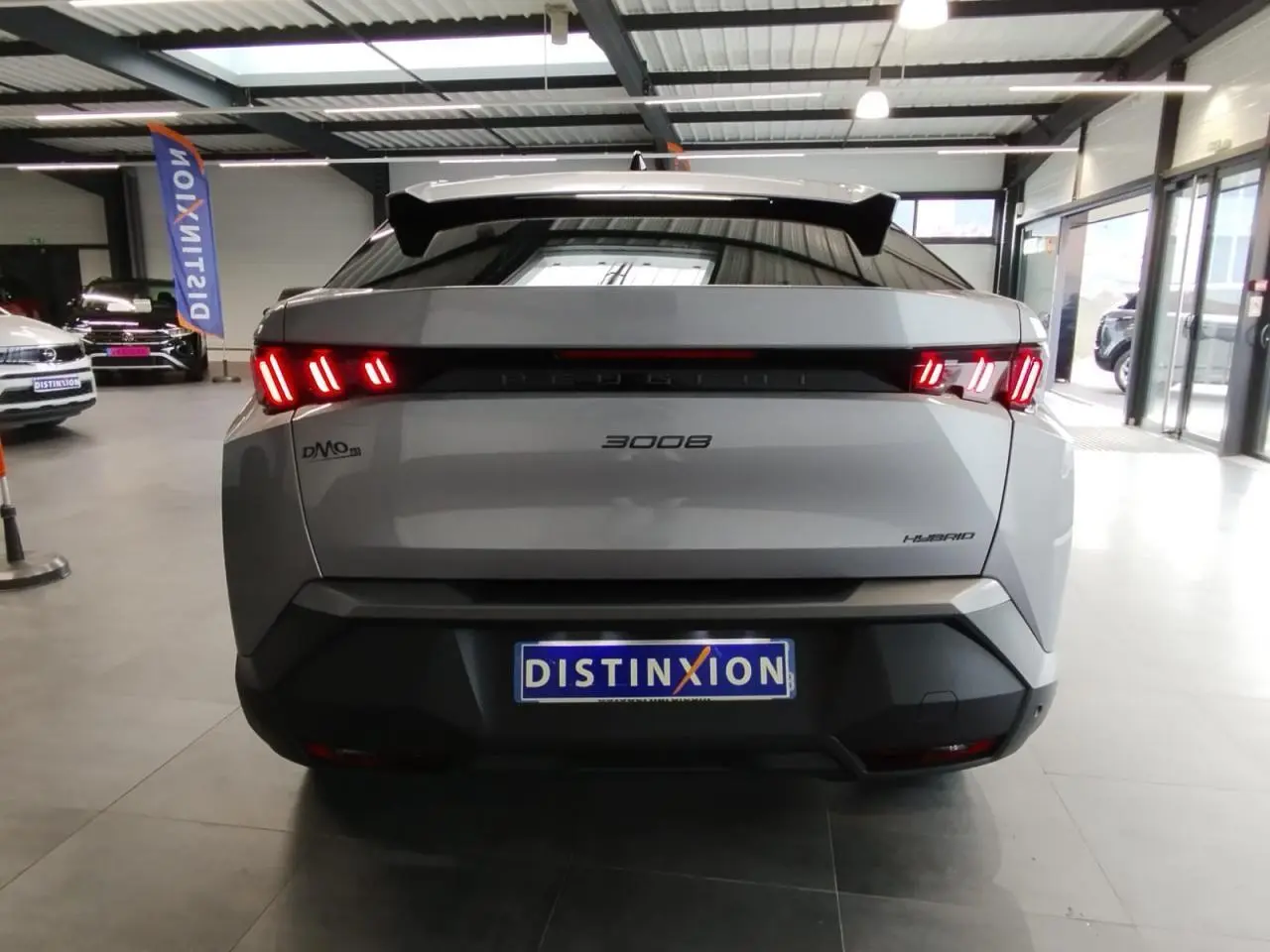 Vue arrière d'un Peugeot 3008 hybride gris Artense avec feux arrière LED 3 griffes et bandeau noir laqué.