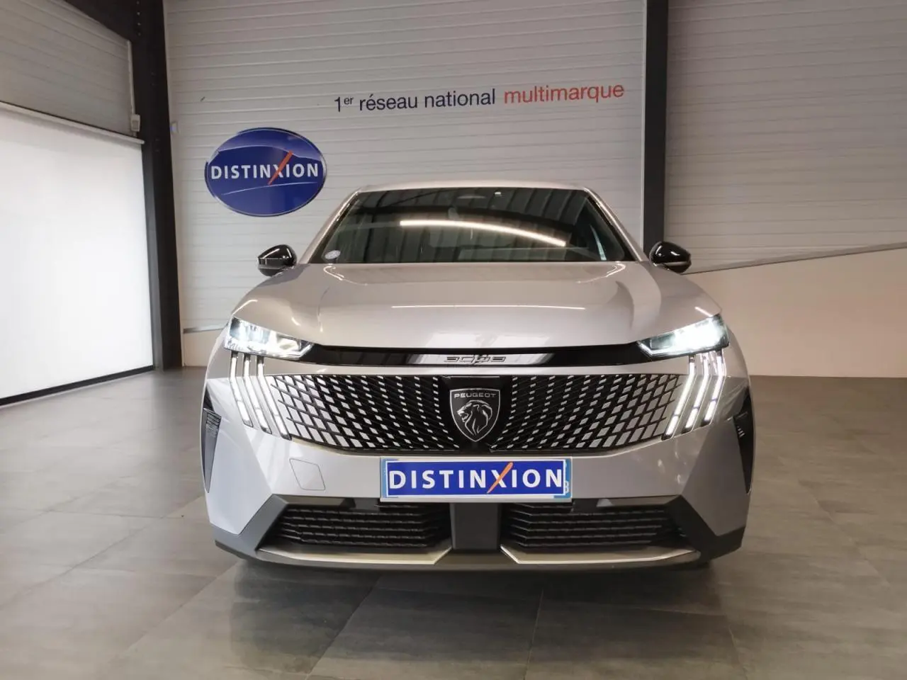 Vue frontale du Peugeot 3008 gris Artense avec calandre distinctive et feux LED en griffes allumés.