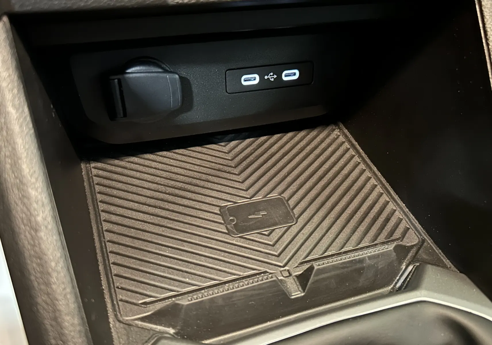 Gros plan sur la console centrale du Dacia Duster 2024, montrant un espace de rangement avec ports USB et prise 12V.