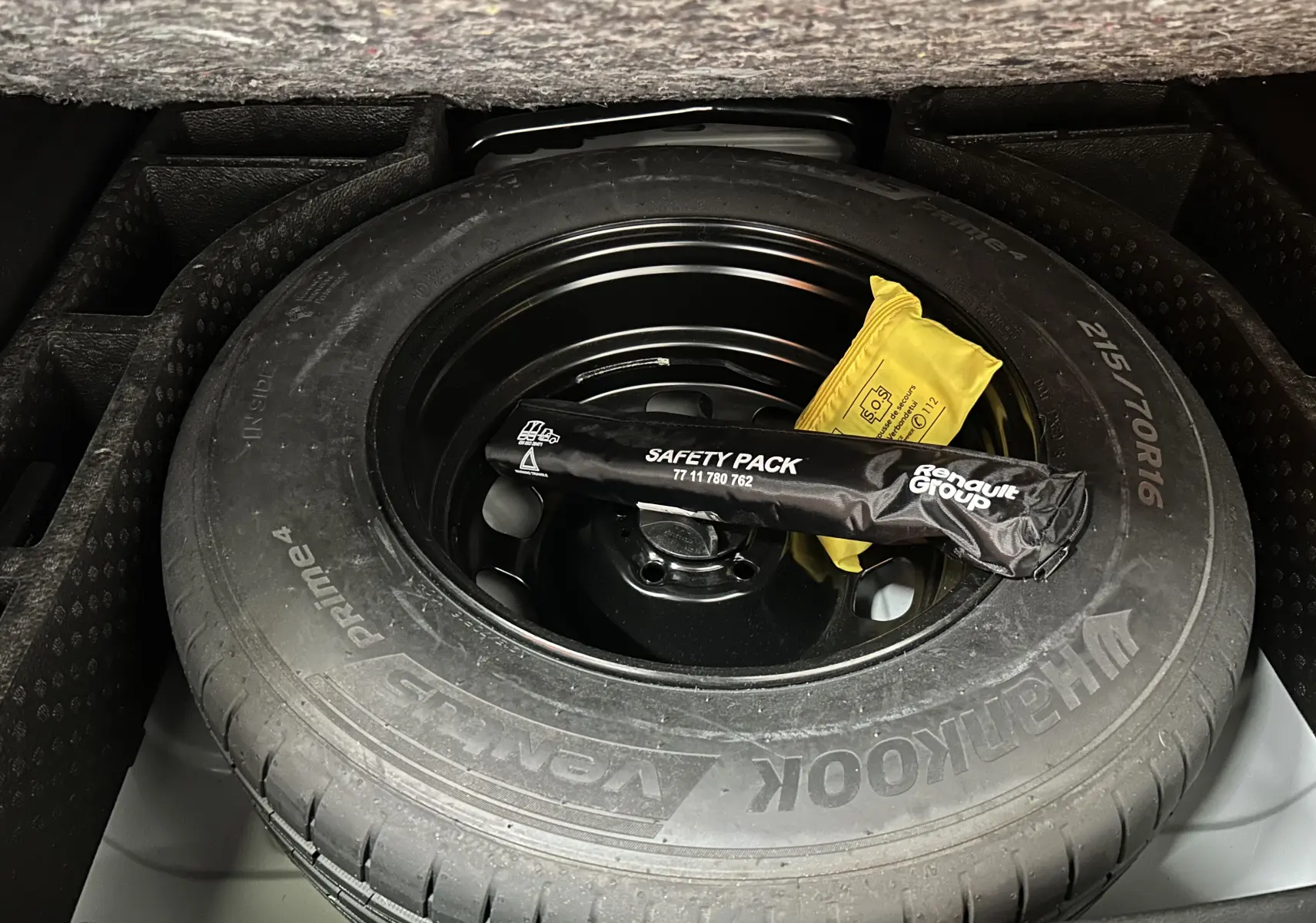 Gros plan sur la roue de secours Hankook dans le coffre du Dacia Duster 2024, avec kit de sécurité Renault posé dessus.