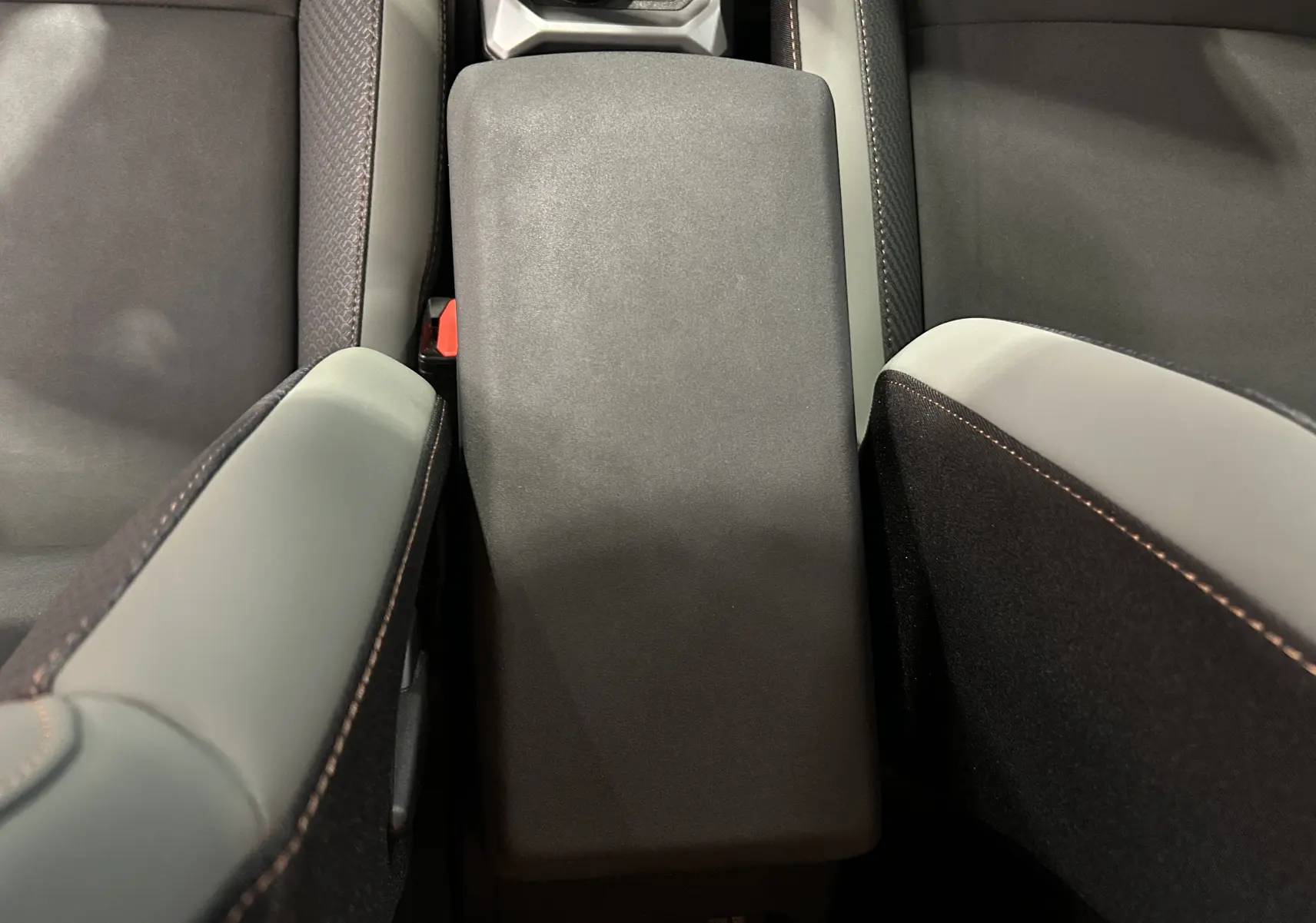 Vue rapprochée de l'accoudoir central et des sièges gris clair et noir du Dacia Duster 2024, version TCE 130 4x4.