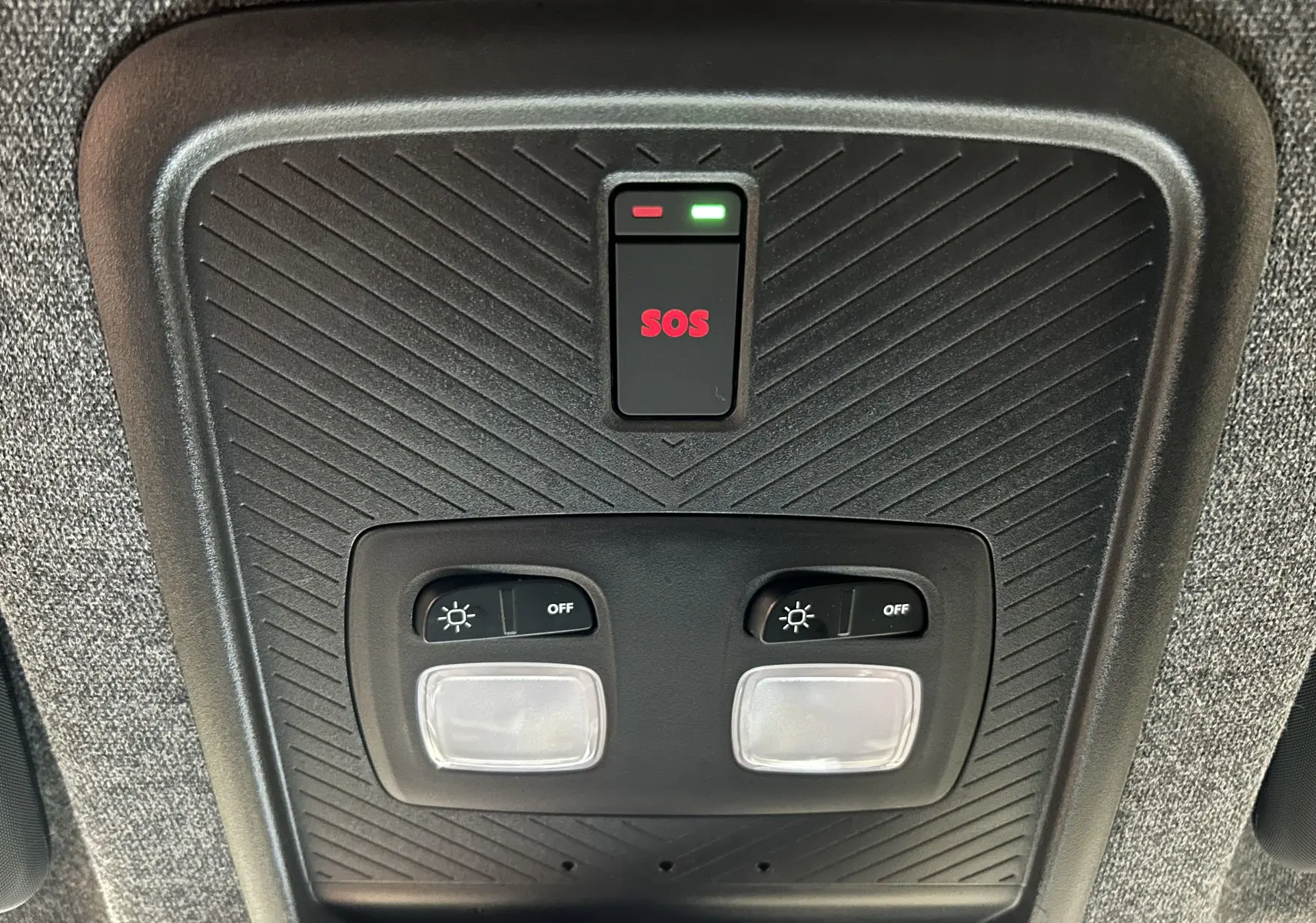 Plafonnier intérieur noir avec boutons d'éclairage et bouton SOS rouge dans un Dacia Duster 2024.