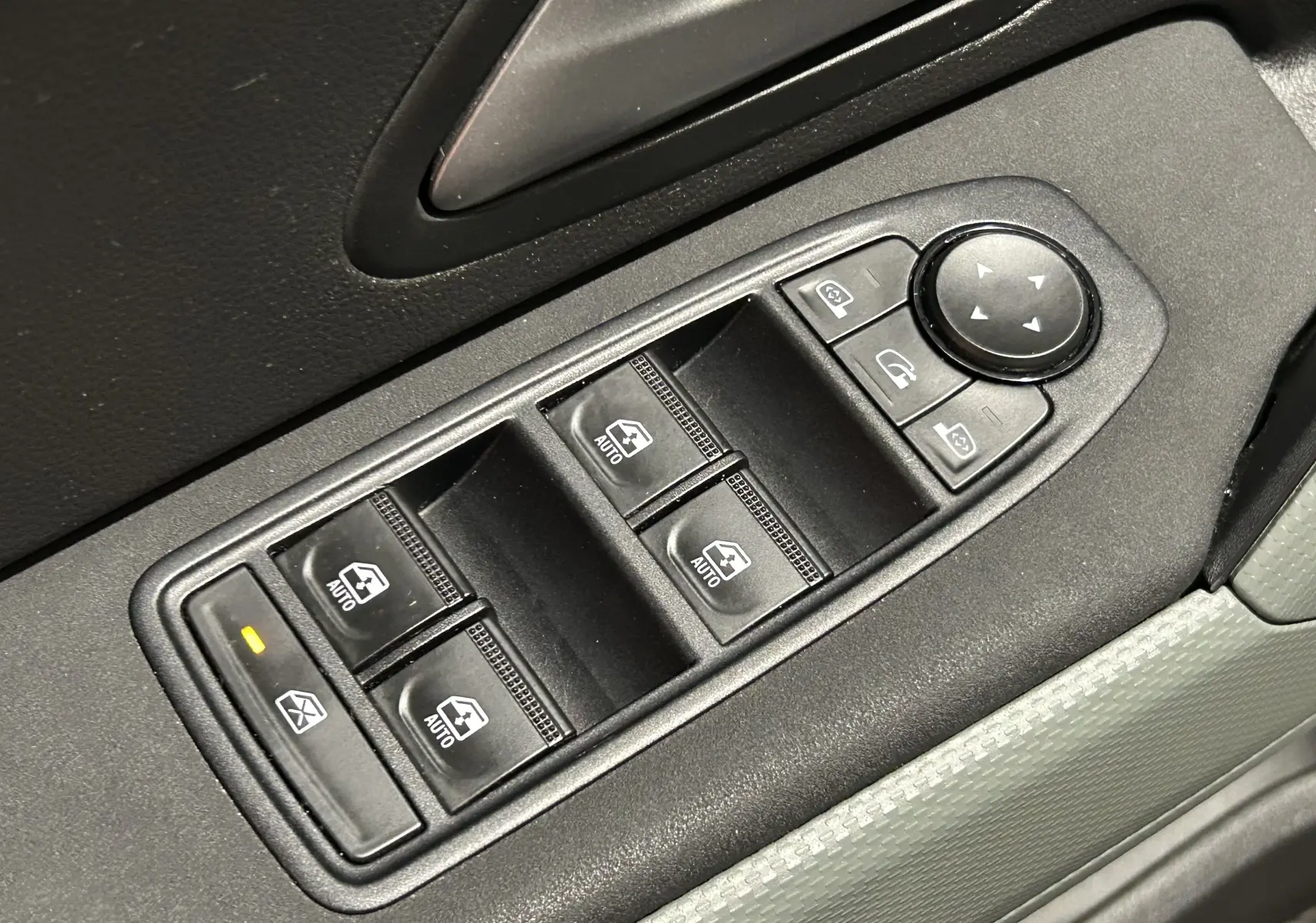 Gros plan sur les commandes électriques des vitres et rétroviseurs côté conducteur du Dacia Duster 2024 couleur Sandstone.