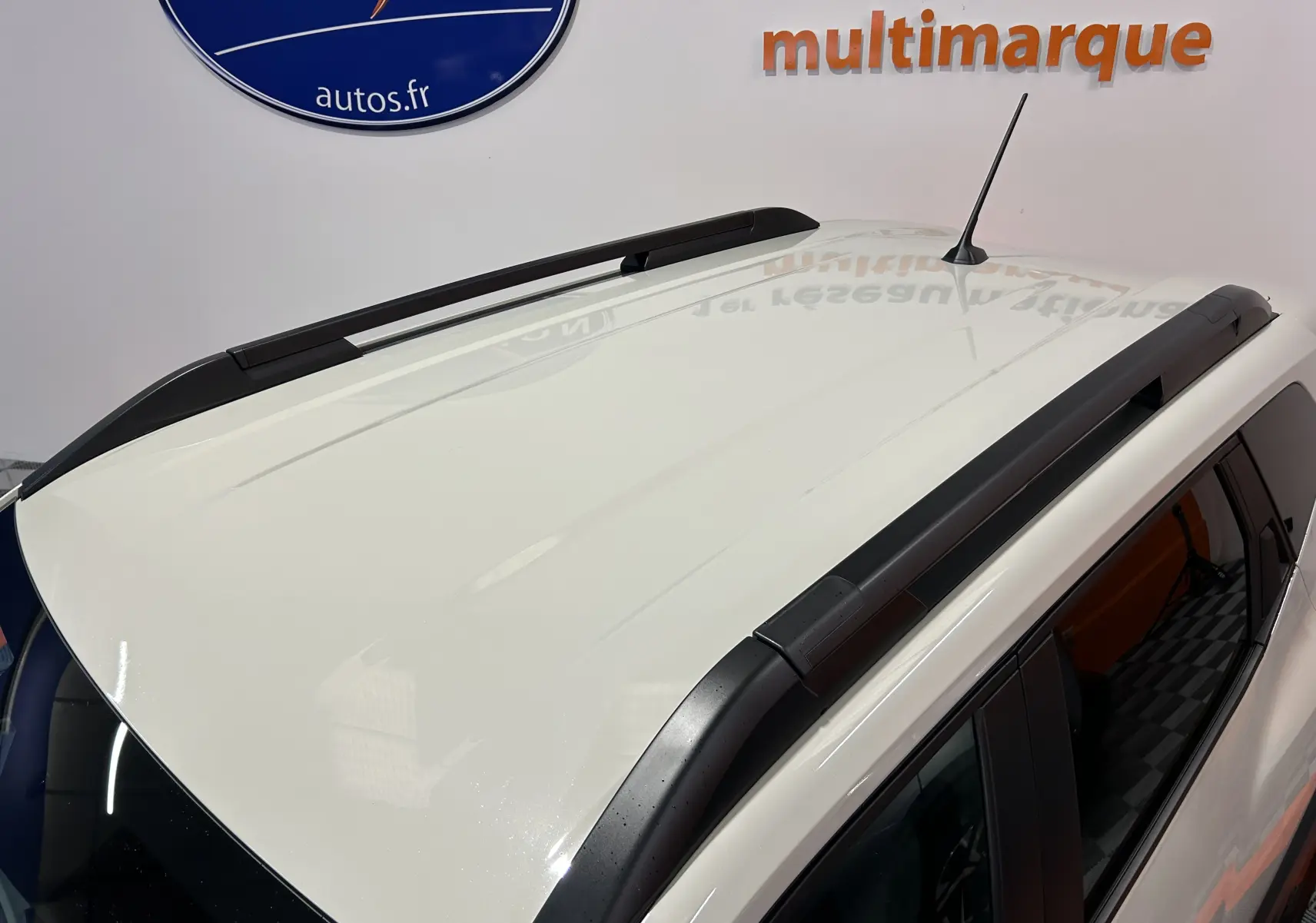 Vue en plongée du toit blanc du Dacia Duster 2024 avec barres de toit noires et antenne centrale.