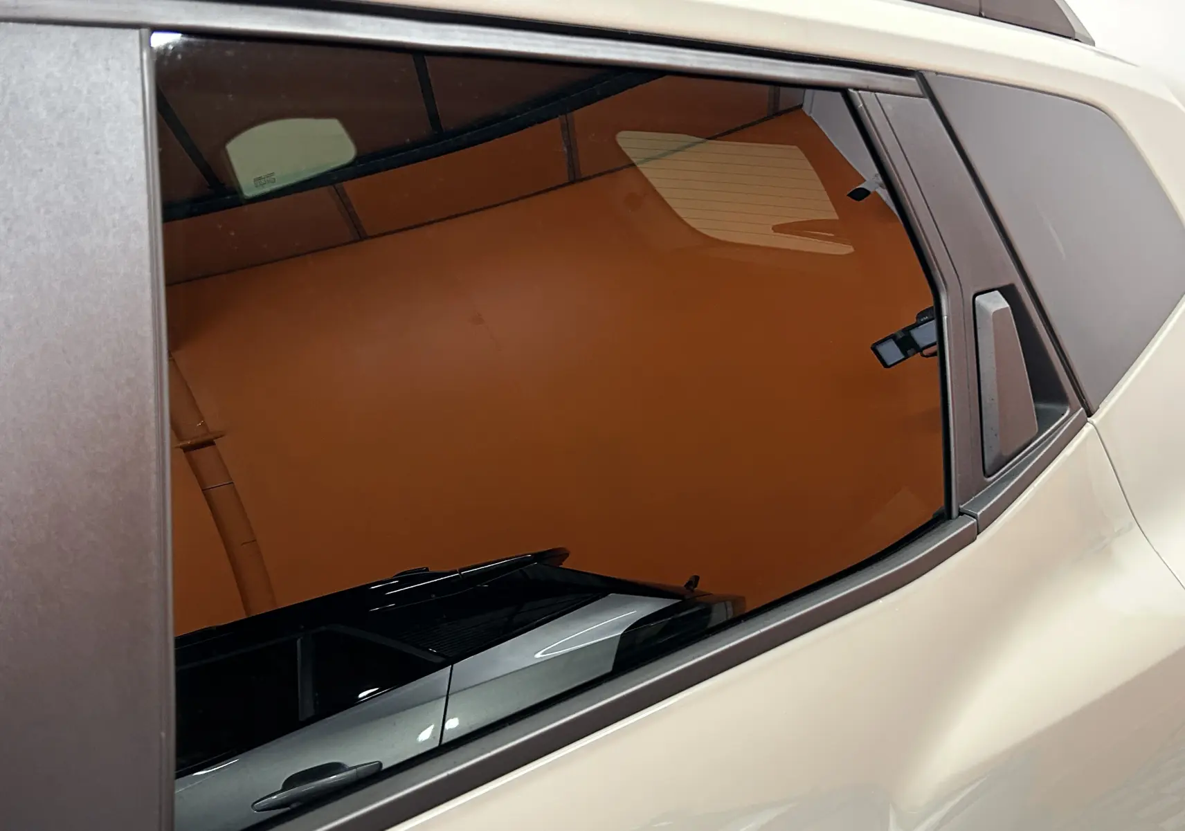 Vue rapprochée sur la vitre arrière côté droit du Dacia Duster 2024 couleur Sandstone avec entourage noir mat.