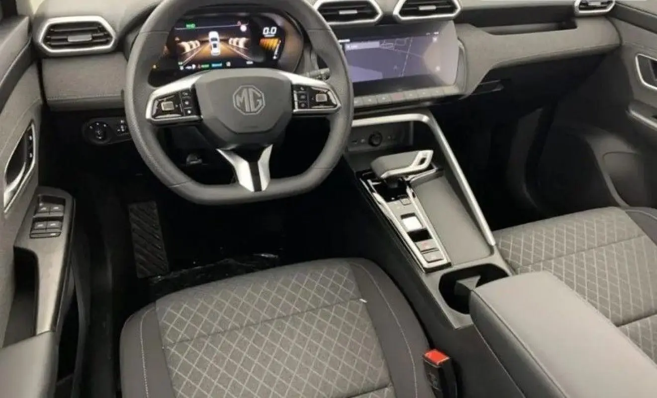 Vue intérieure avant du MG ZS 2026 avec volant multifonction, tableau de bord digital et sièges tissu gris à motifs.
