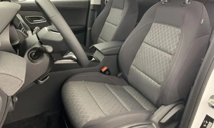 Vue intérieure côté conducteur du MG ZS 1.5L Hybrid+ 2026, sièges tissu gris avec surpiqûres en losange.