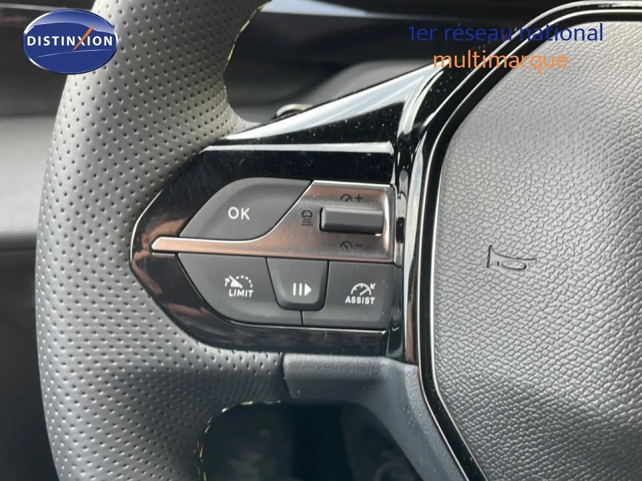 Gros plan sur la partie gauche du volant perforé de la Peugeot 308 gris Artense, avec commandes de régulateur et assistant.