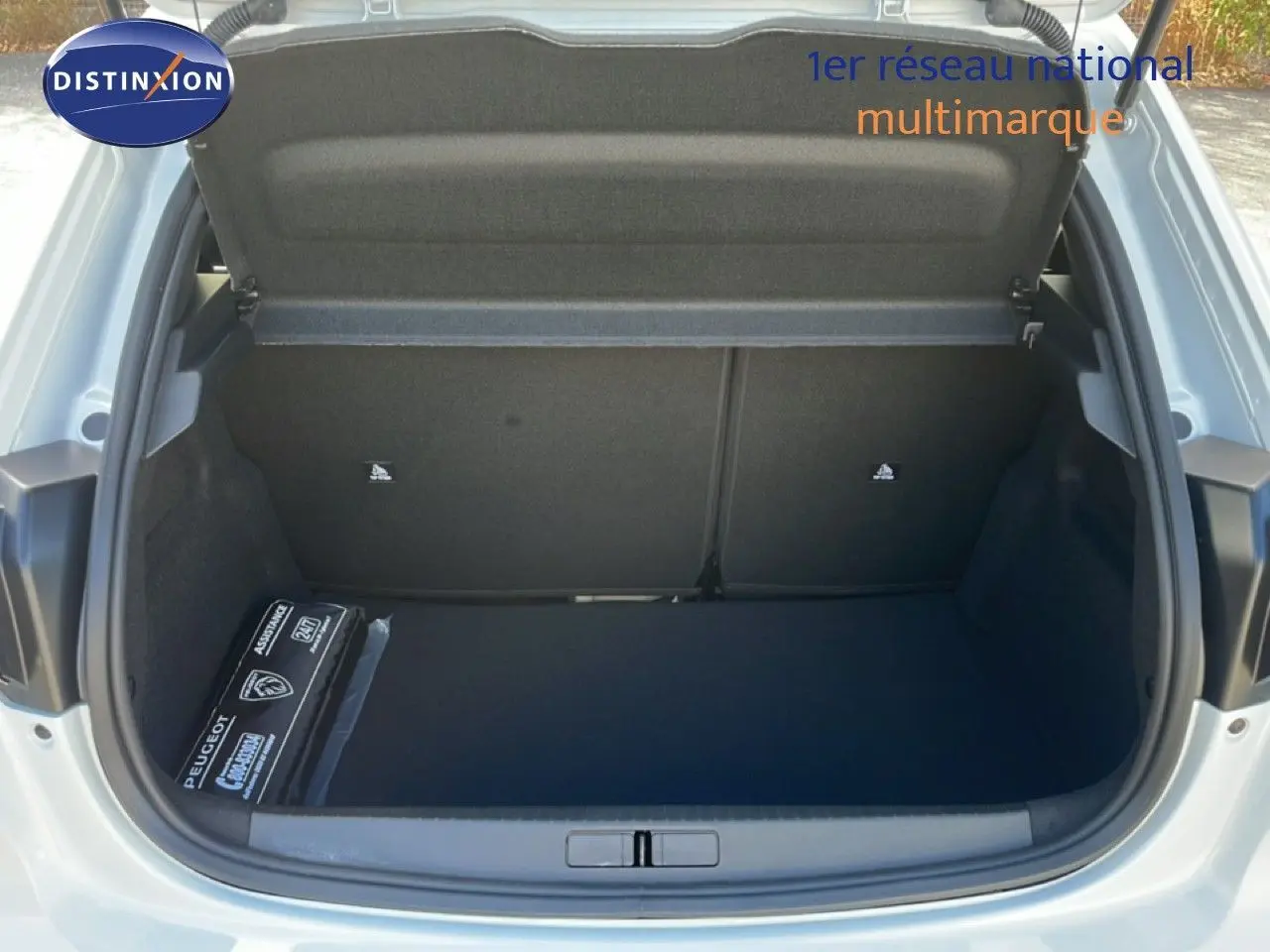 Coffre ouvert d’une Peugeot 208 Hybrid blanc Okenite, vue arrière montrant un espace de rangement propre et spacieux.