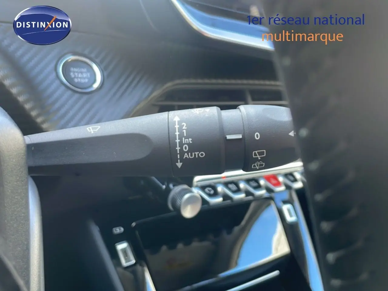 Gros plan sur la commande d’essuie-glace et le bouton start/stop du tableau de bord d’une Peugeot 208 blanche.