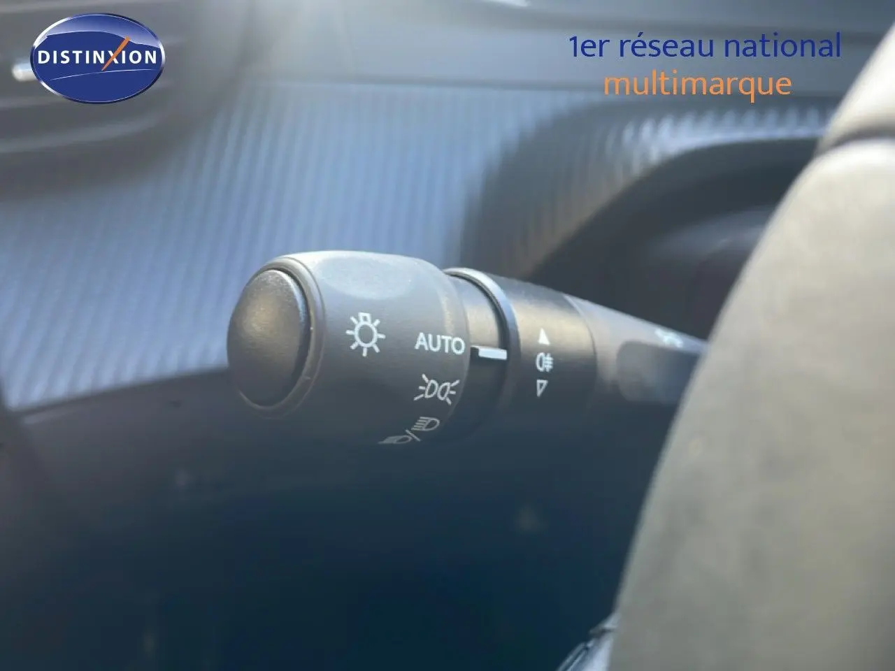 Gros plan sur la commande des phares automatique à gauche du volant dans une Peugeot 208 blanche hybride 2026.