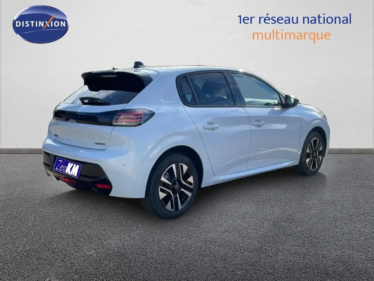 Vue 3/4 arrière droite d'une Peugeot 208 hybride blanche Okenite Metal avec jantes noires et détails noirs contrastants.