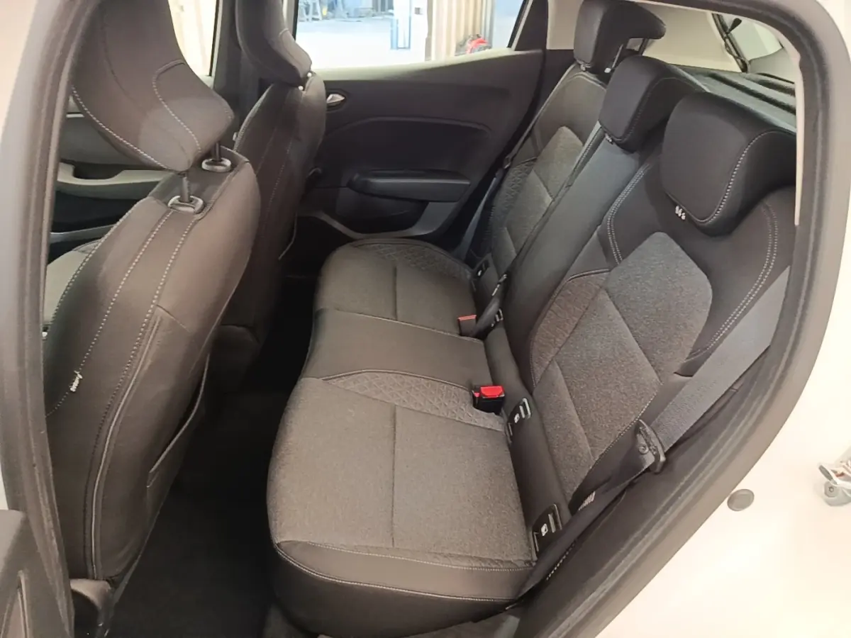 Vue latérale intérieure montrant la banquette arrière grise et noire d'une Renault Clio blanche, porte arrière ouverte.
