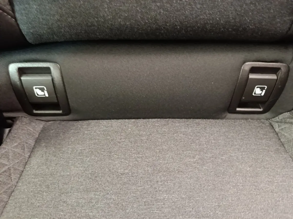 Détail des commandes de rabattement des sièges arrière en tissu gris dans une Renault Clio Business E-TECH 140 blanche.