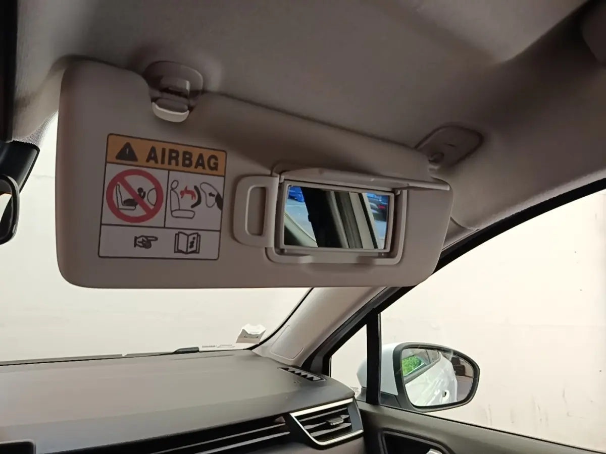 Intérieur Renault Clio blanc, vue côté passager avec pare-soleil relevé et miroir de courtoisie visible.