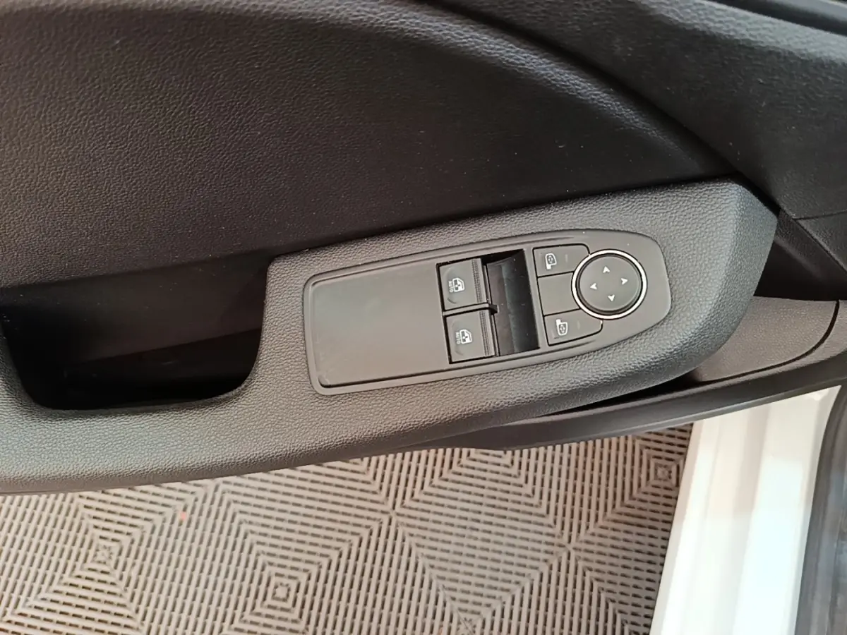 Gros plan sur la commande des vitres électriques côté conducteur de la Renault Clio Business E-TECH blanche, porte ouverte.