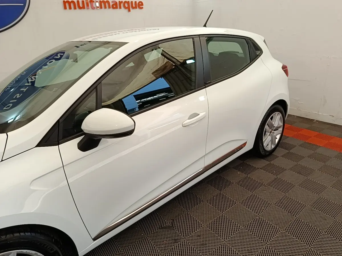 Profil côté gauche de la Renault Clio Business E-TECH blanche 2021 avec rétroviseur et jante visibles.