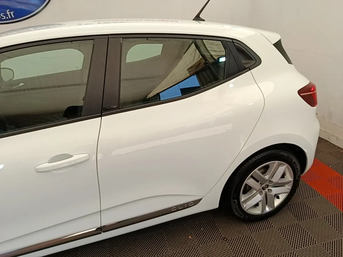 Vue latérale droite d'une Renault Clio blanche Business E-TECH 140 avec jantes alliage et logo Clio sur la bas de porte.