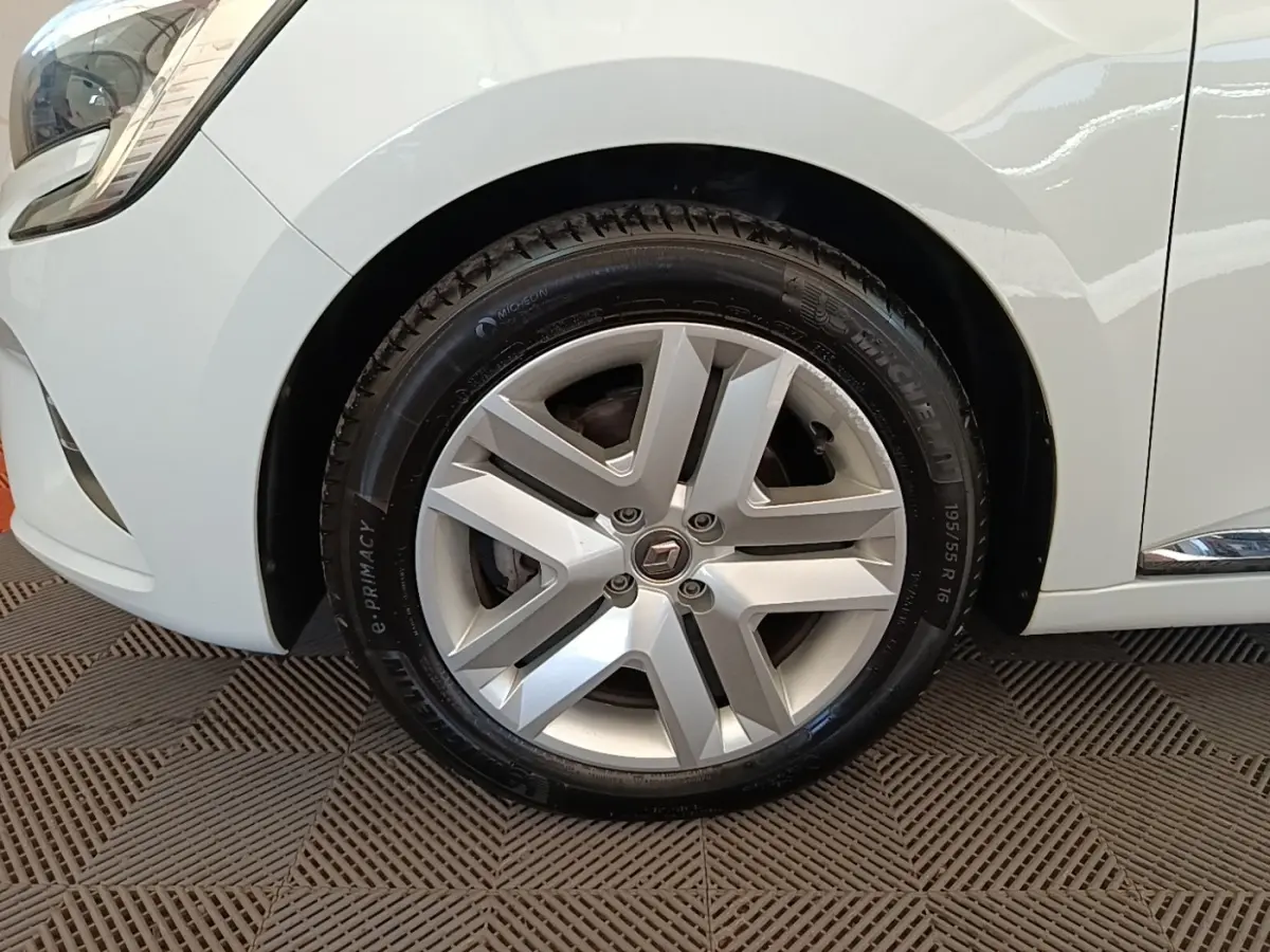 Gros plan sur la roue avant gauche d'une Renault Clio blanche, mettant en valeur la jante alliage et le pneu Michelin.