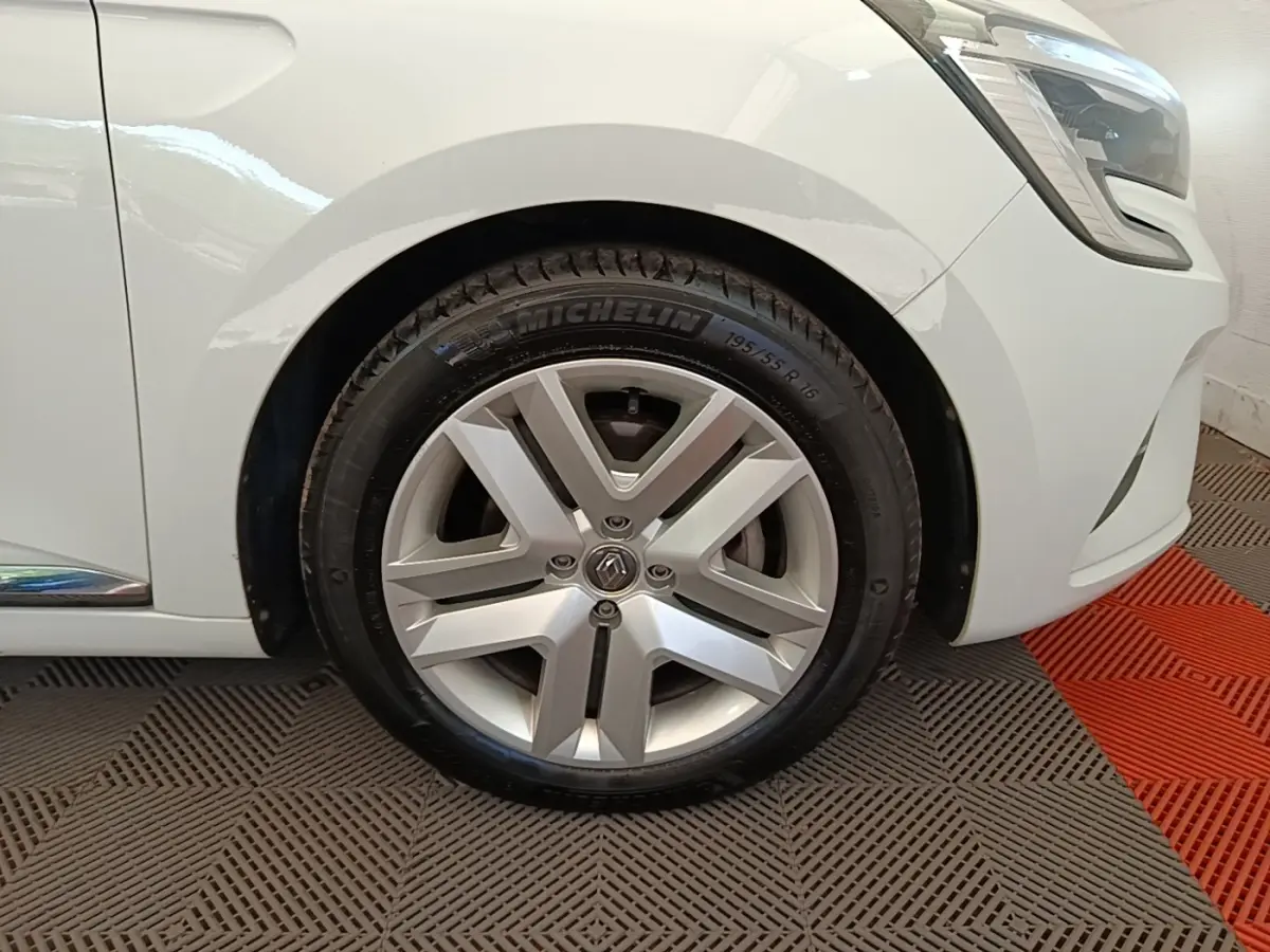 Gros plan sur la roue avant droite et partie du pare-chocs avant d'une Renault Clio Business E-TECH blanche.