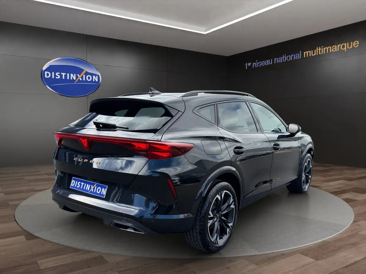 Vue 3/4 arrière droite d'un CUPRA Formentor noir brillant avec feux arrière LED distinctifs en showroom.