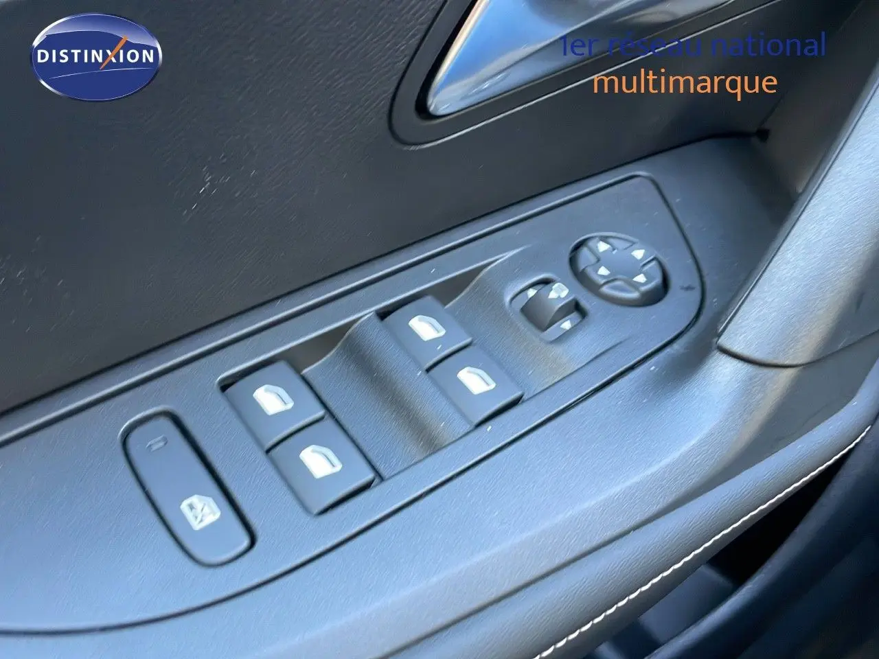 Gros plan sur les commandes des vitres électriques et rétroviseurs sur la porte intérieure d'une Peugeot 2008 gris Artense.