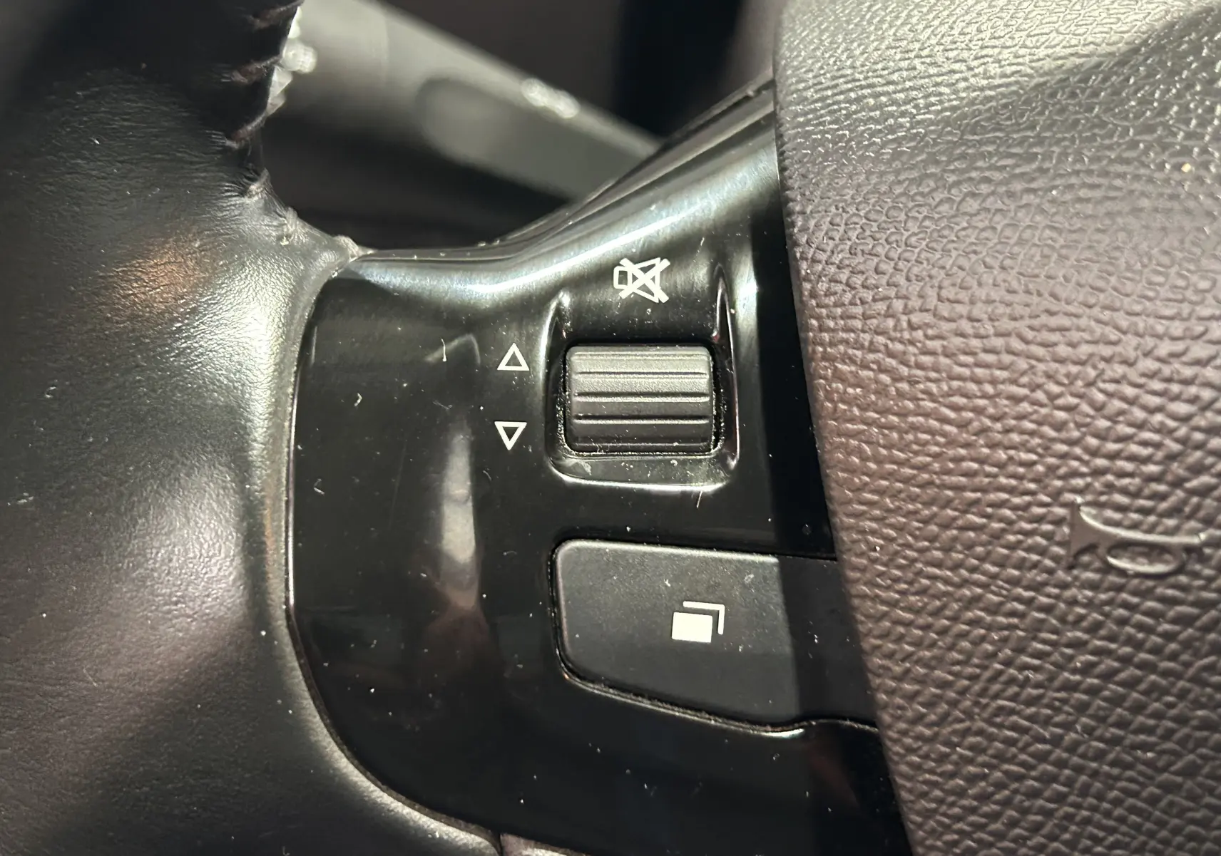 Gros plan sur les commandes de volume et de sourdine sur le volant noir d'une Peugeot 308 gris 2021 Active Pack.