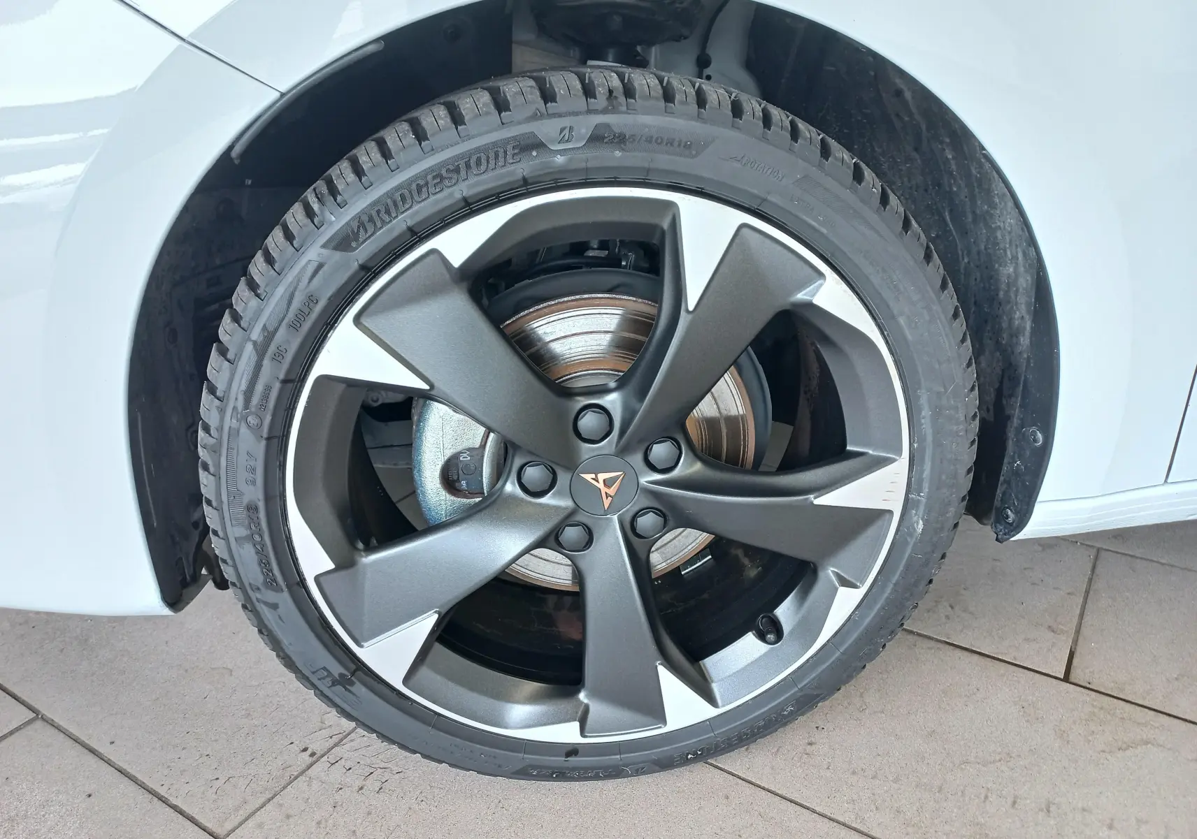 Gros plan sur la roue avant droite d'une CUPRA Leon blanc Nevada avec jante alliage gris foncé et détails argentés.