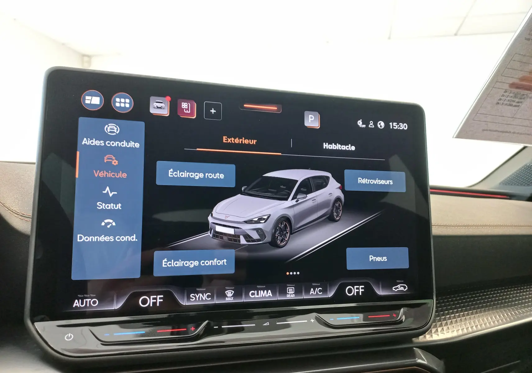 Écran tactile intérieur affichant une vue 3/4 avant d'une CUPRA Leon blanc Nevada avec options d'éclairage et pneus.